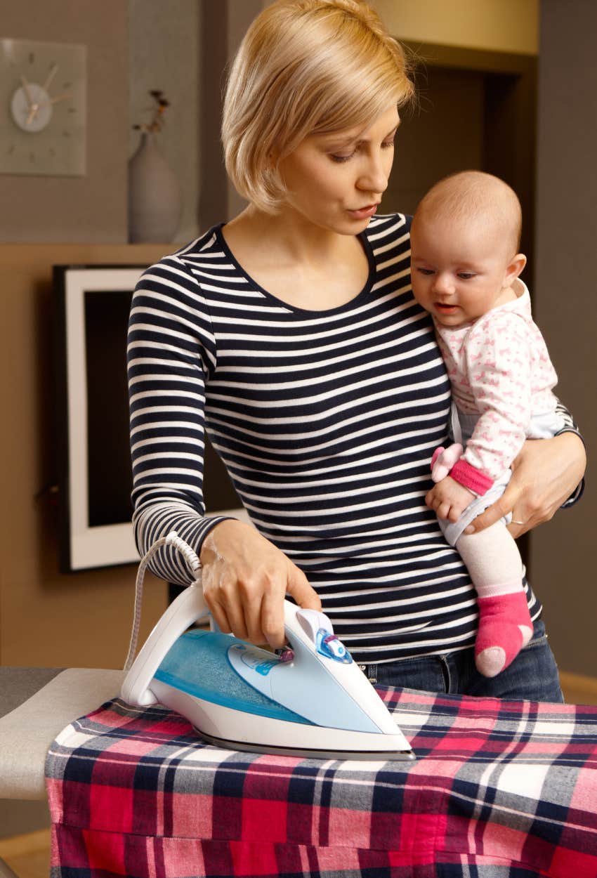 mom holding baby and ironing