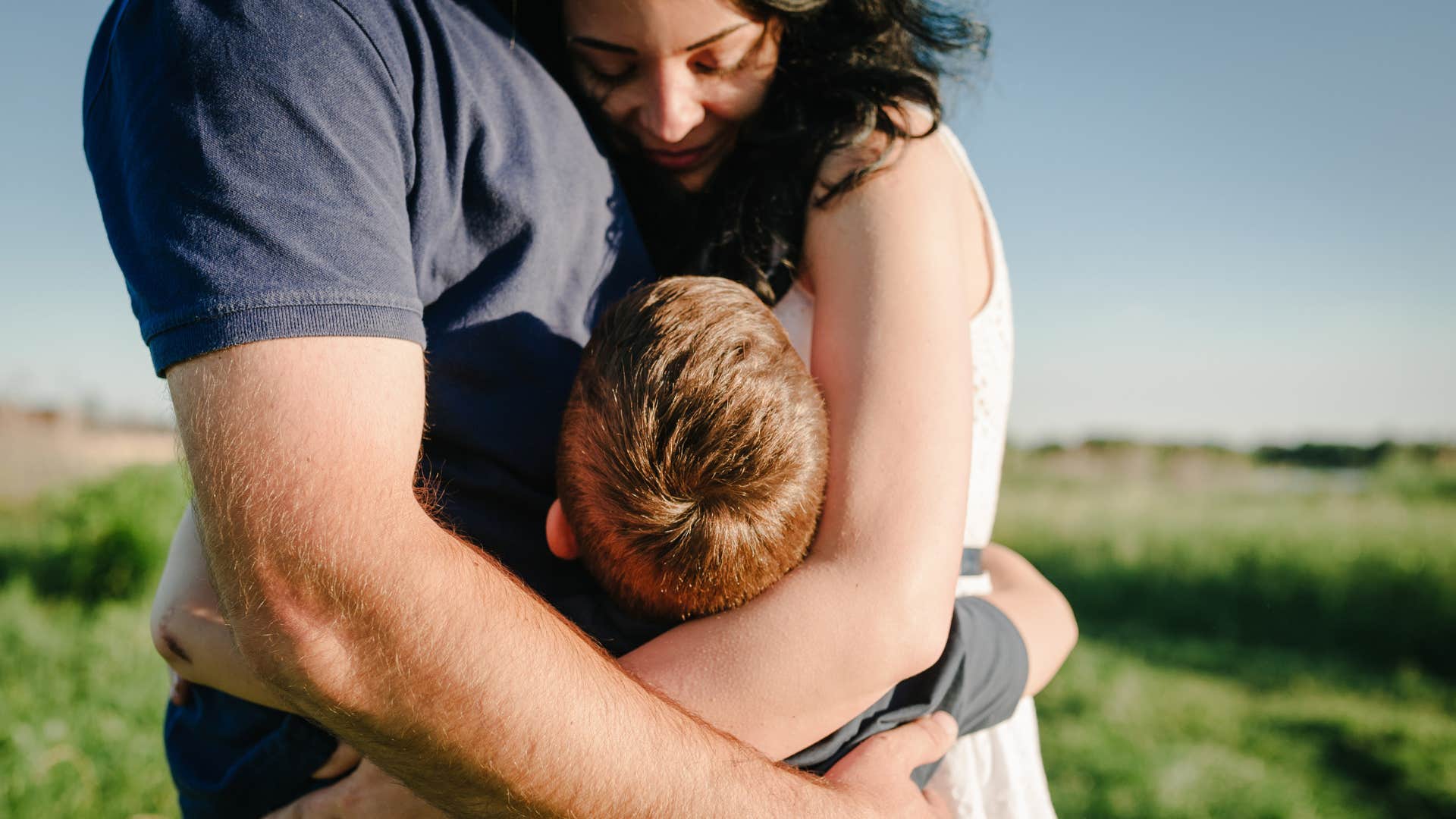  Mom, dad and boy walk in the grass