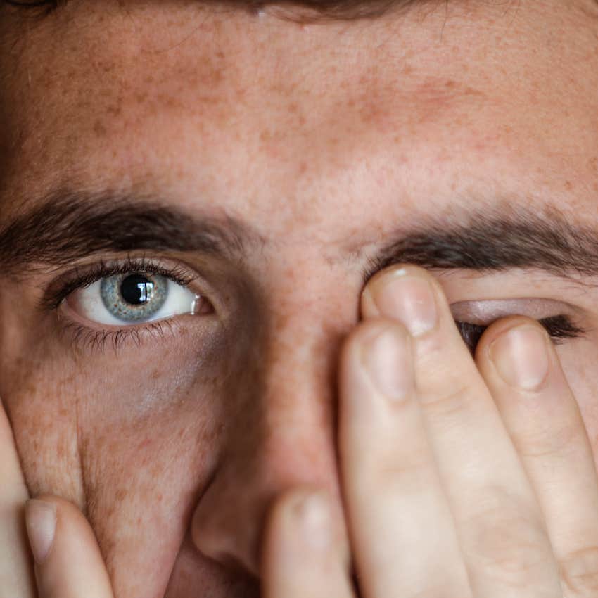 Close up of man's face with one hand over one eye