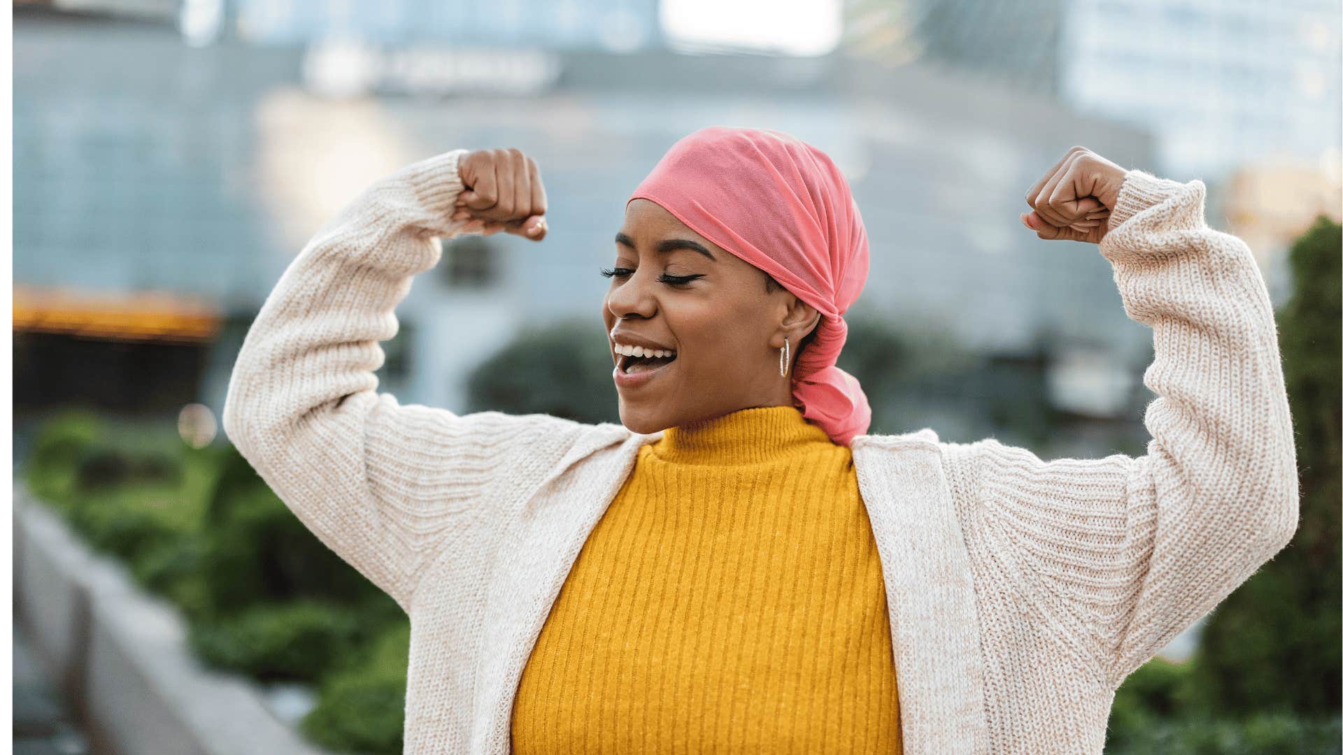 woman with breast cancer smiling with her arms up