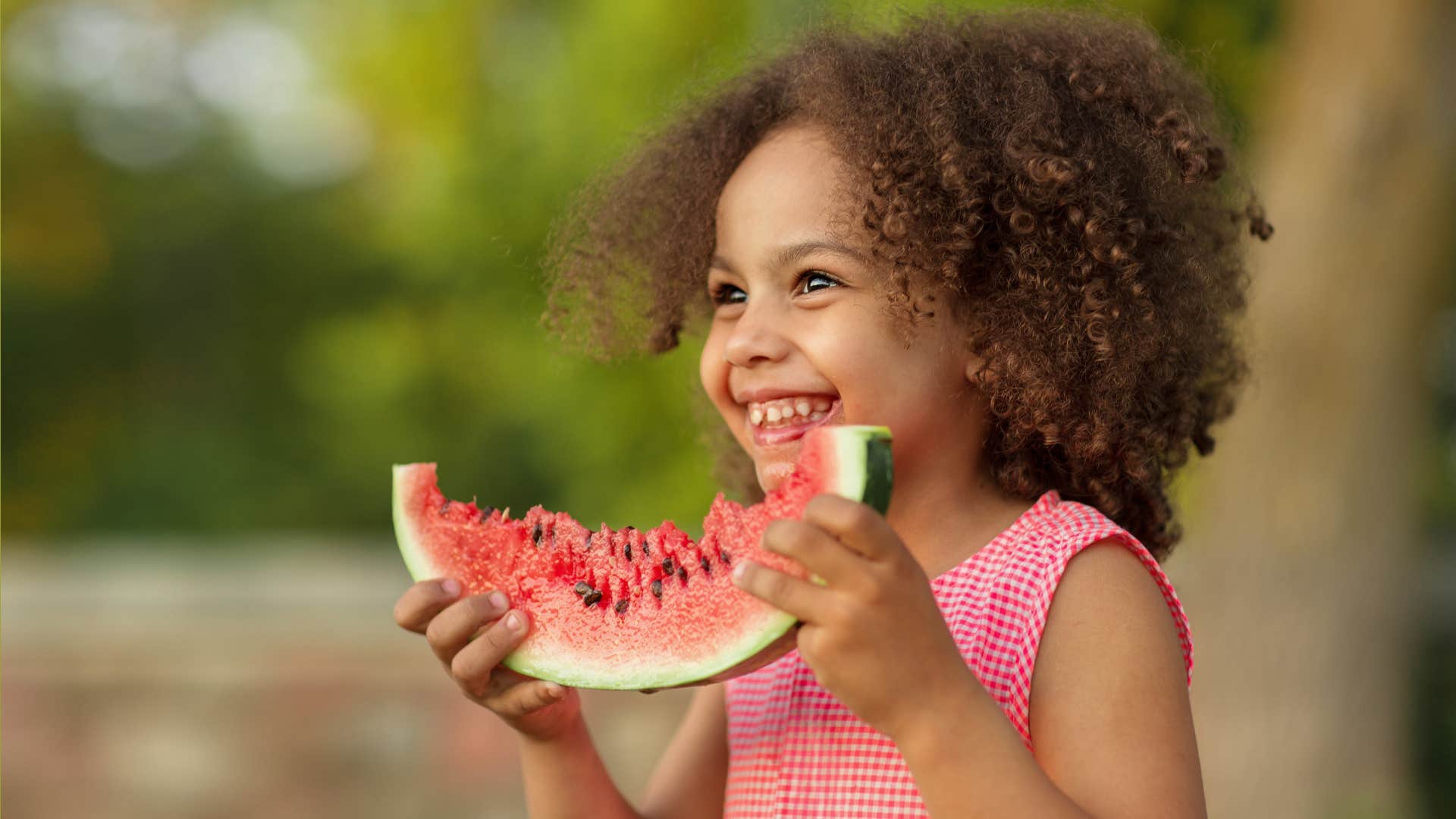 kid eating watermelon outdoors in hot summer