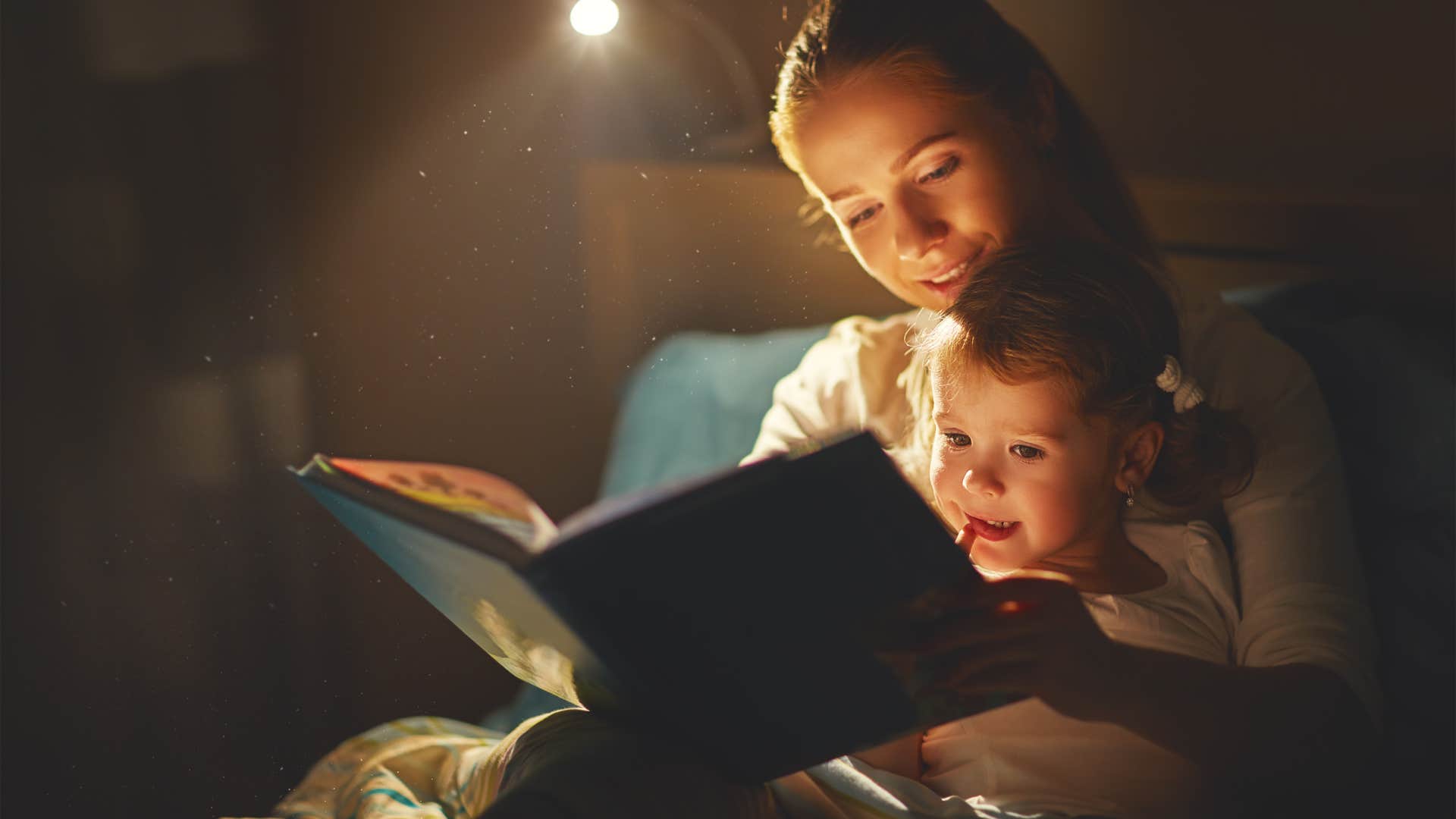 mother and child reading a book in bed before going to sleep