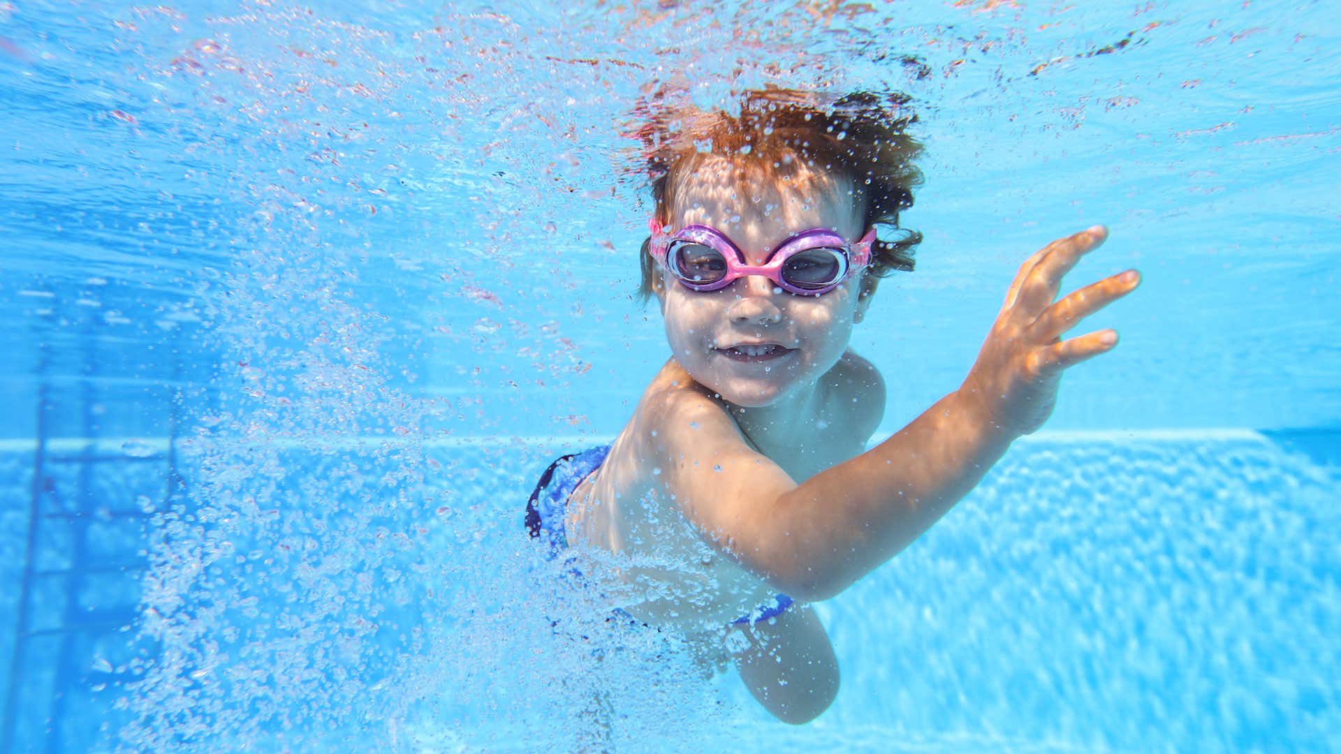 little boy swimming underwater in pool