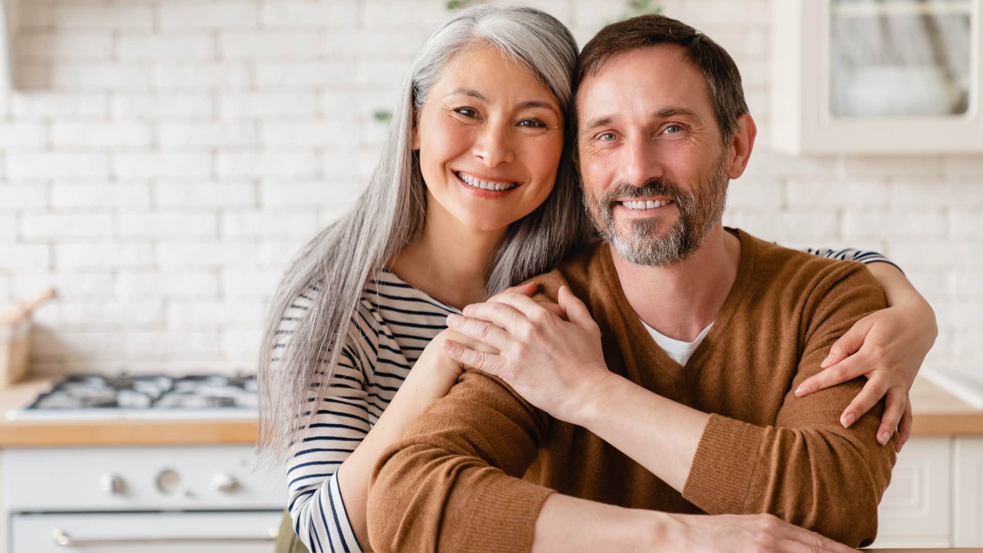 Couple smiling and hugging in a kitchen.