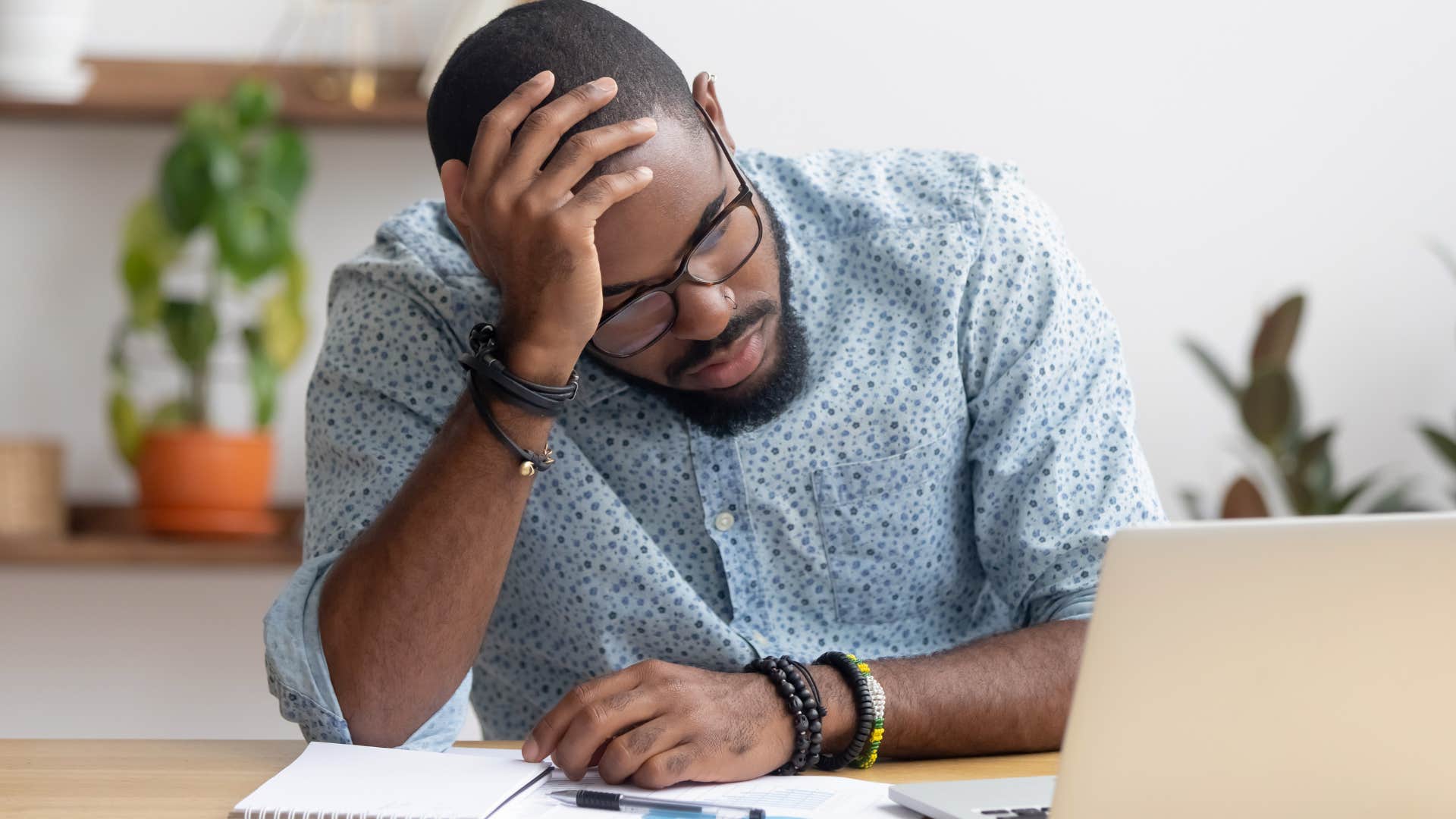 Man working and holding his head in his hands.