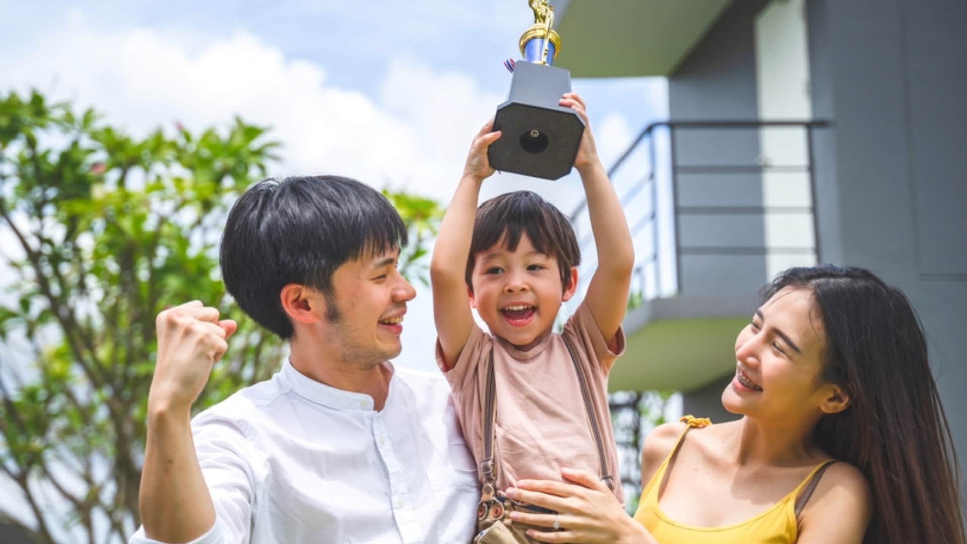 millennial couple and child holding trophy