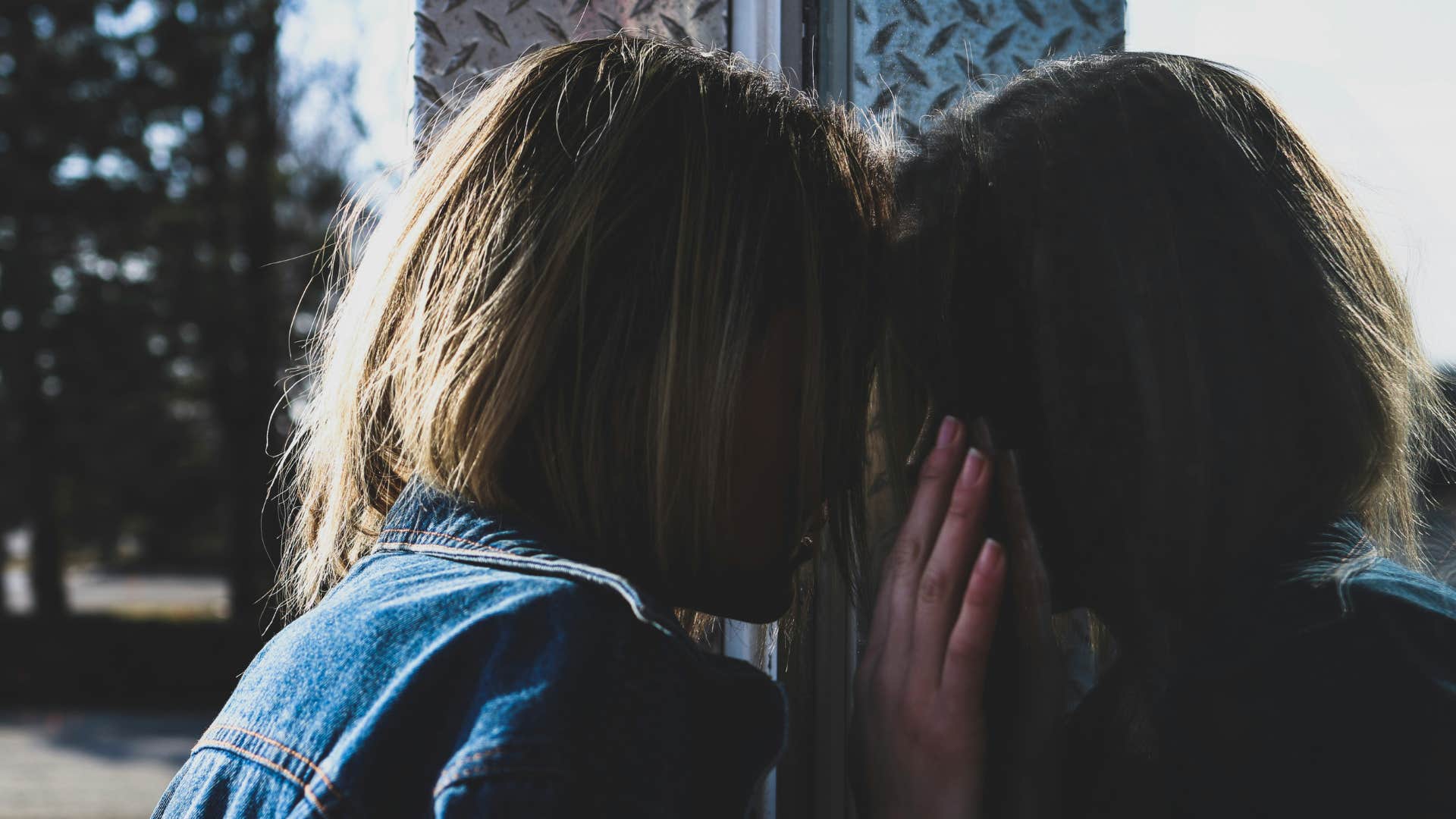 woman in jean jacket leaning her head on the window