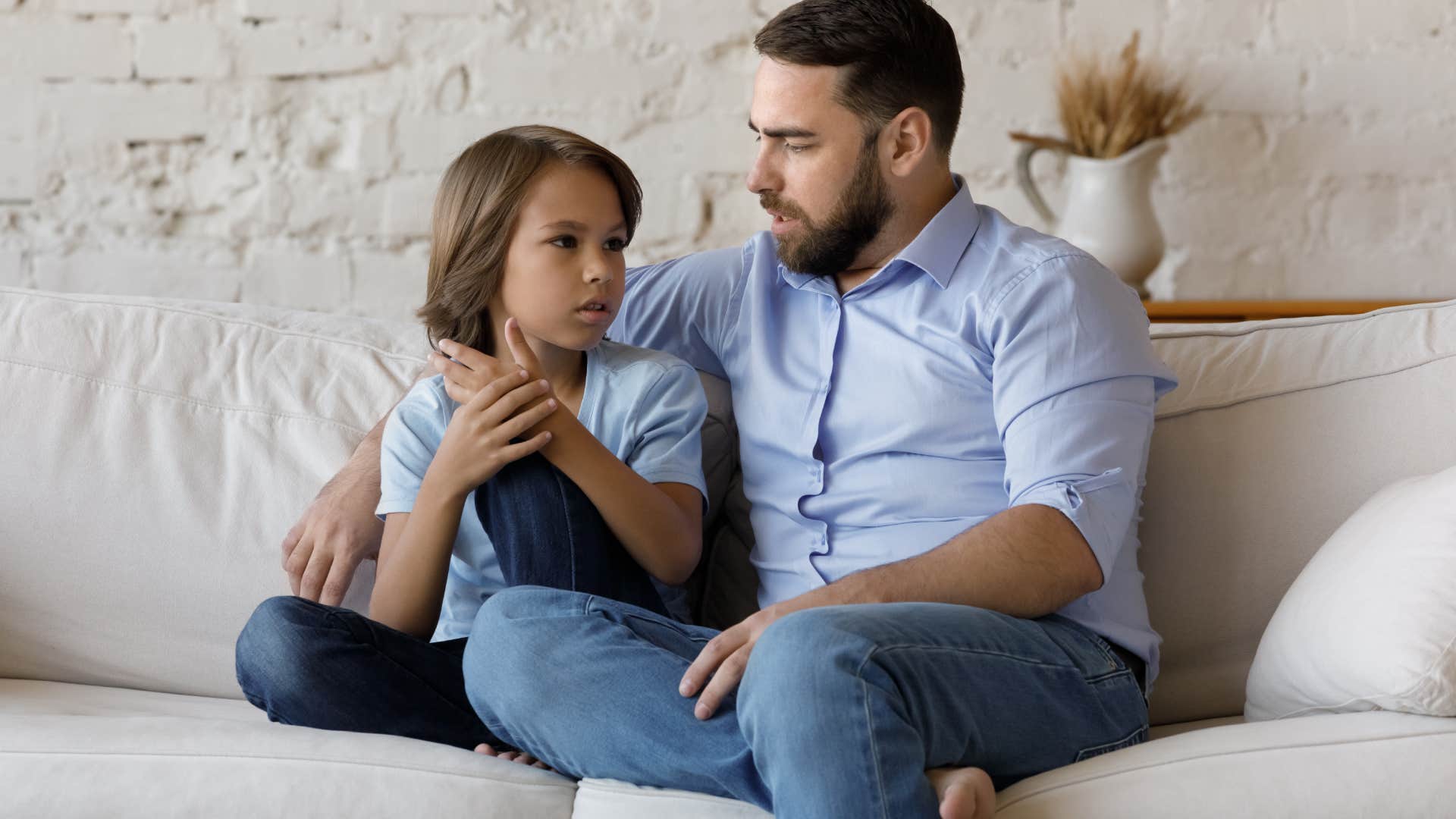 father having conversation with son on couch