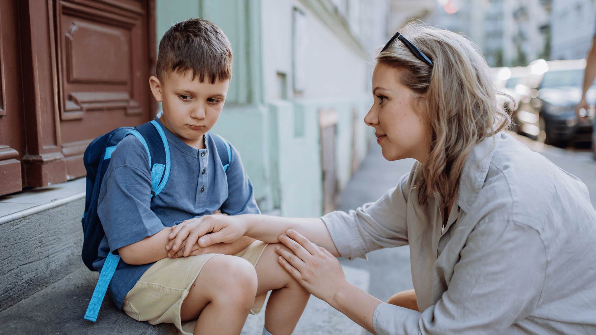 upset young boy outside woth mother