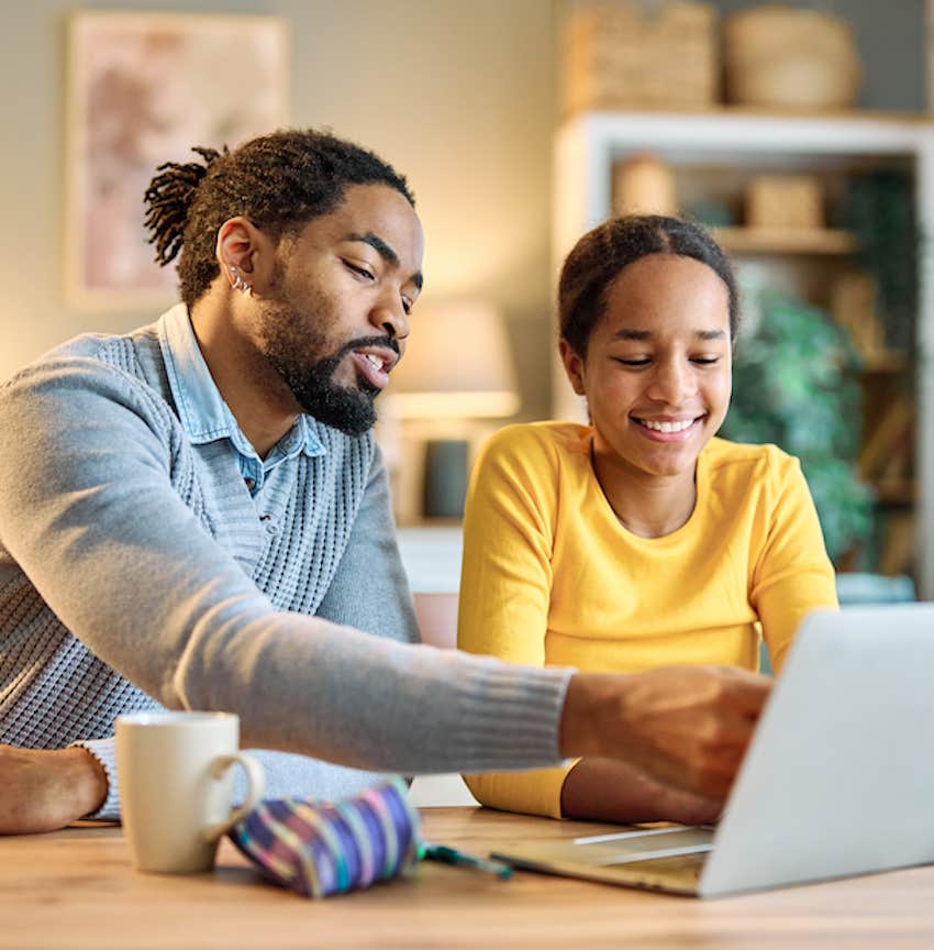 Parent and child happily work together on laptop