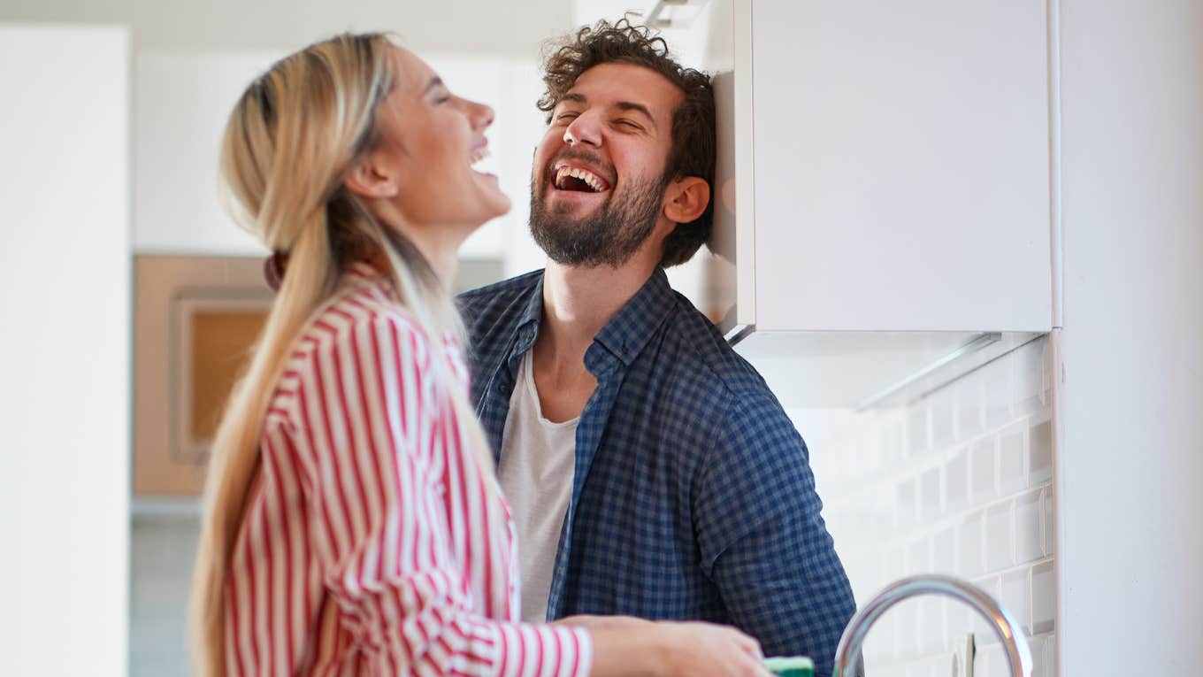 man and wife laughing together in the kitchen