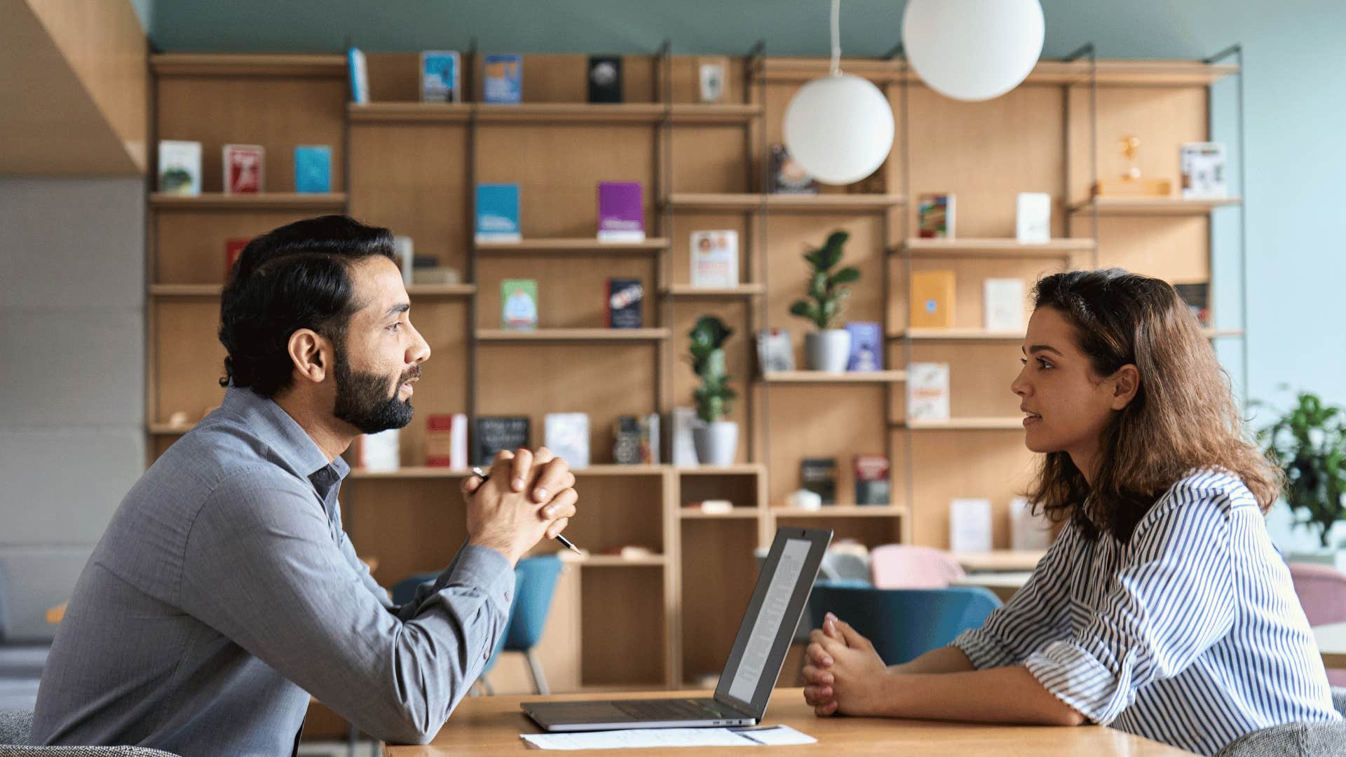 man talking to woman across from him at desk