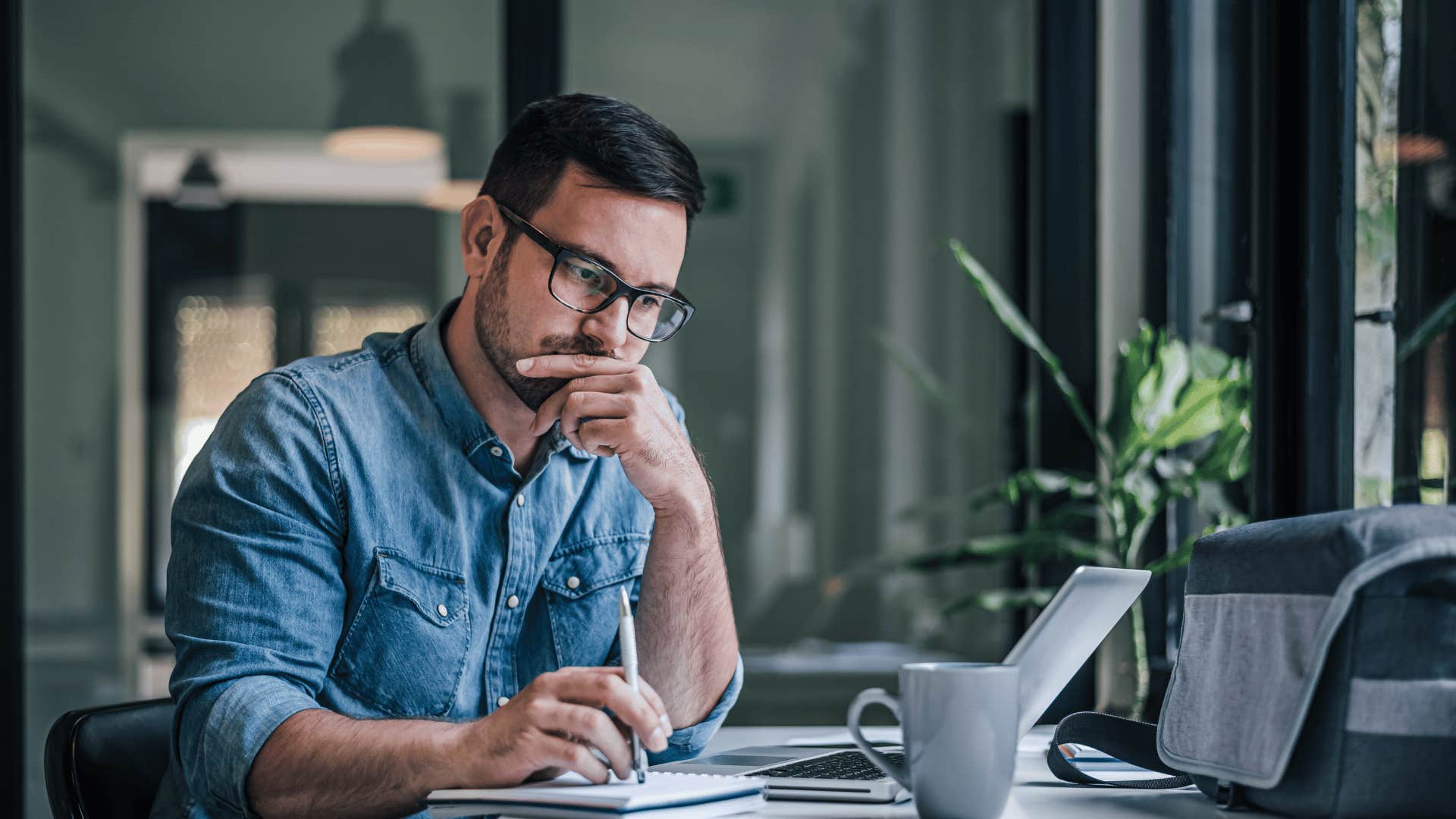 man thinking and writing in notebook