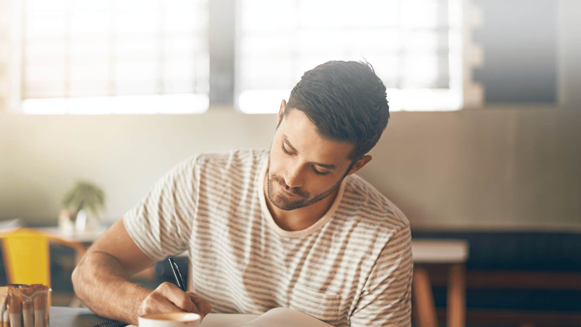 man writing in journal