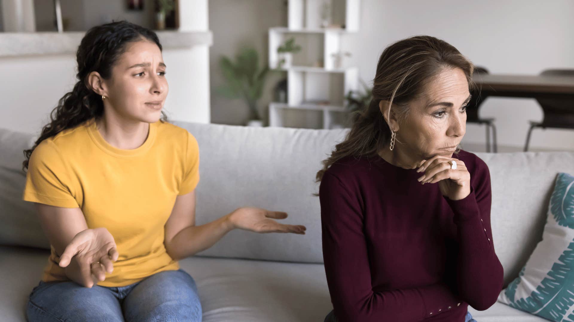 older woman ignoring young daughter on couch