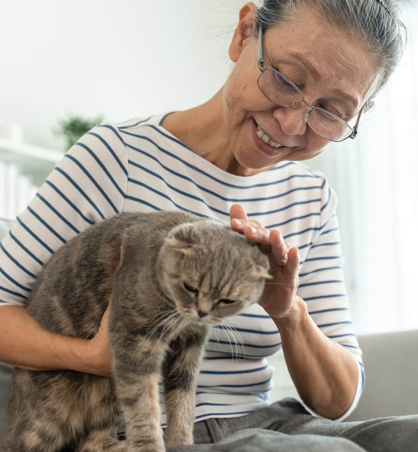 Elder woman happily pets her cat 