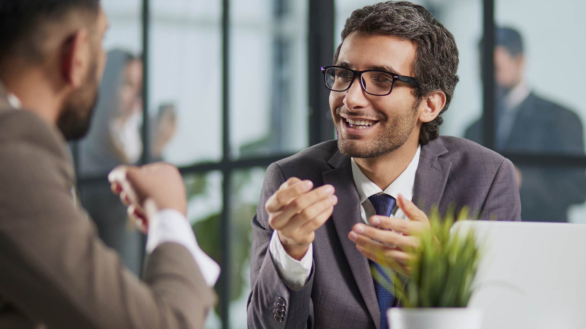 Professional man smiling and talking to a peer.