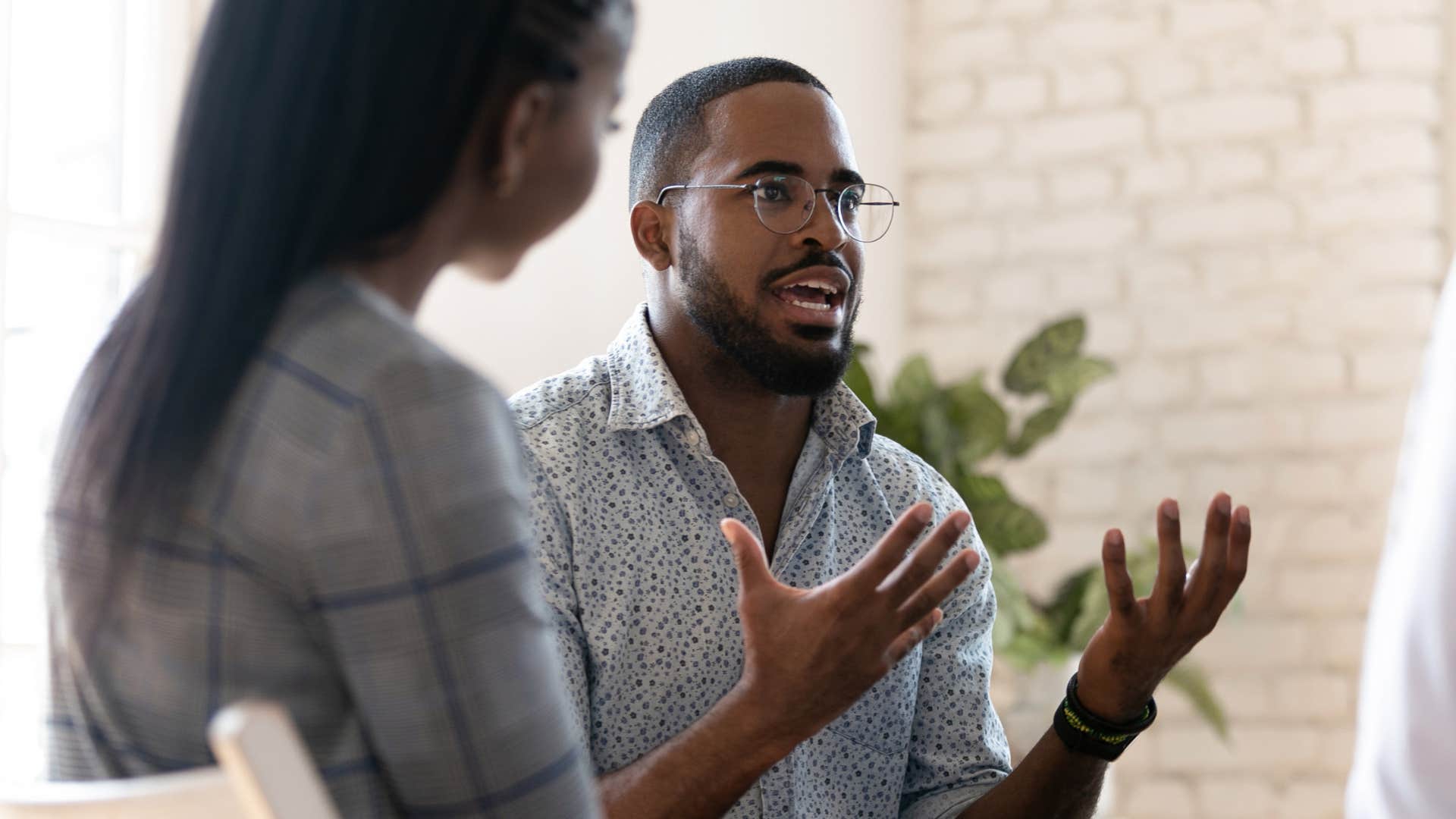 Angry man holding his hands up while talking to a woman.