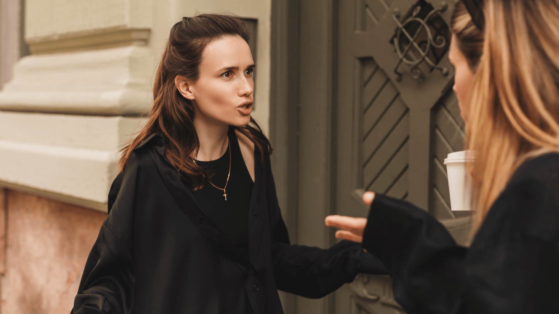 two women arguing outside of building