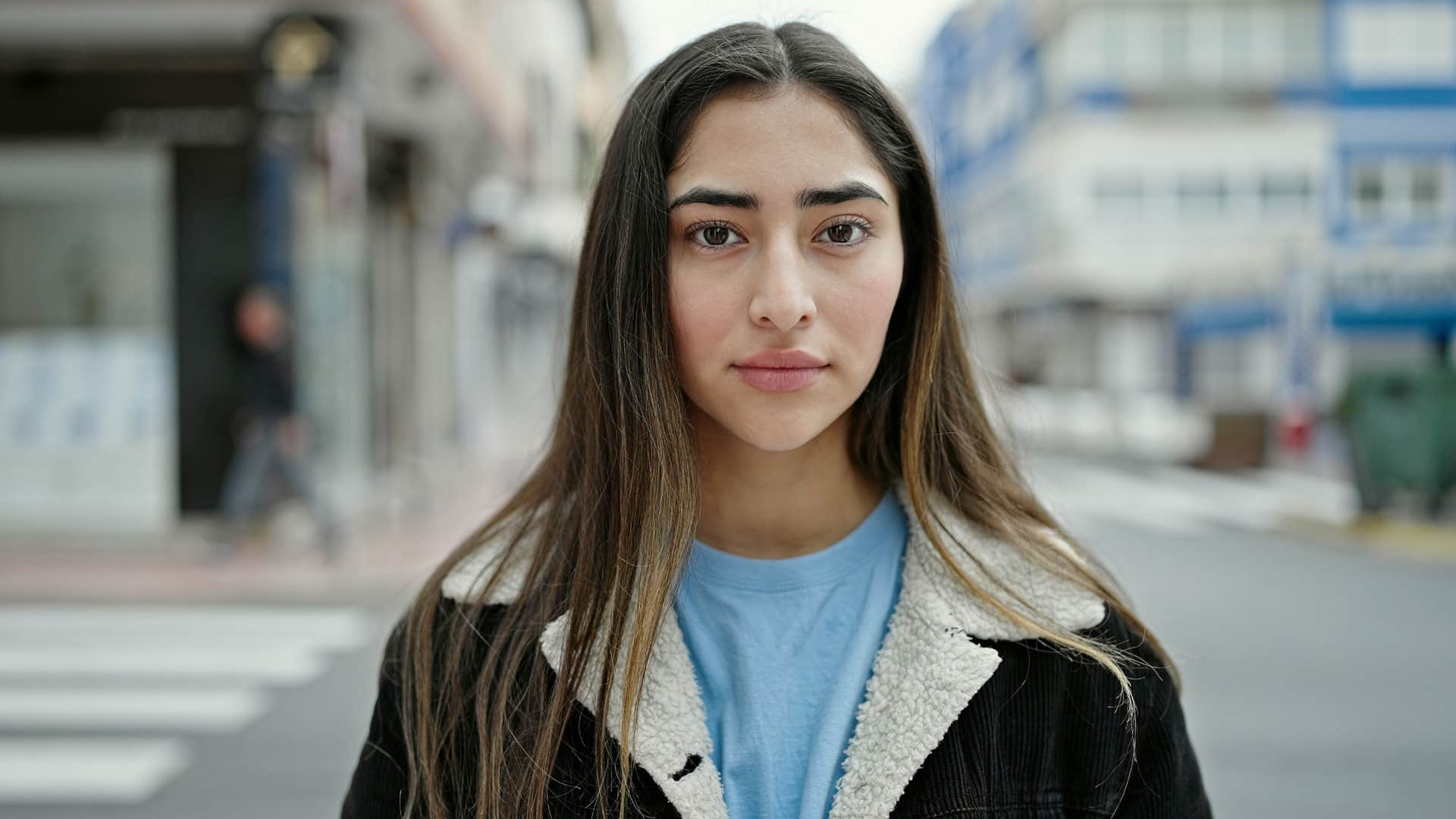 secretly controlling young woman standing on street