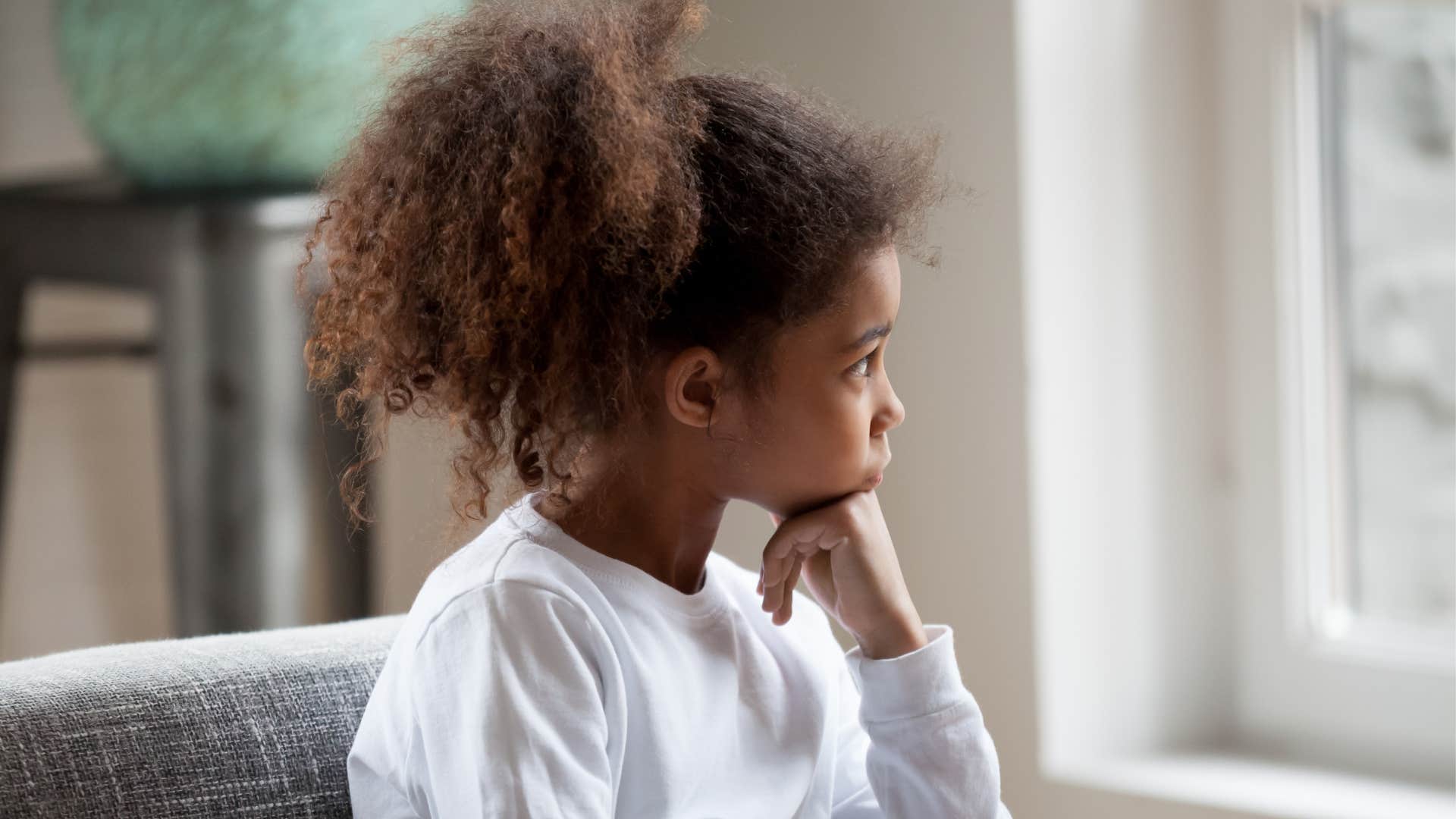 young girl stares out of the window after parents told her she needed to socialize