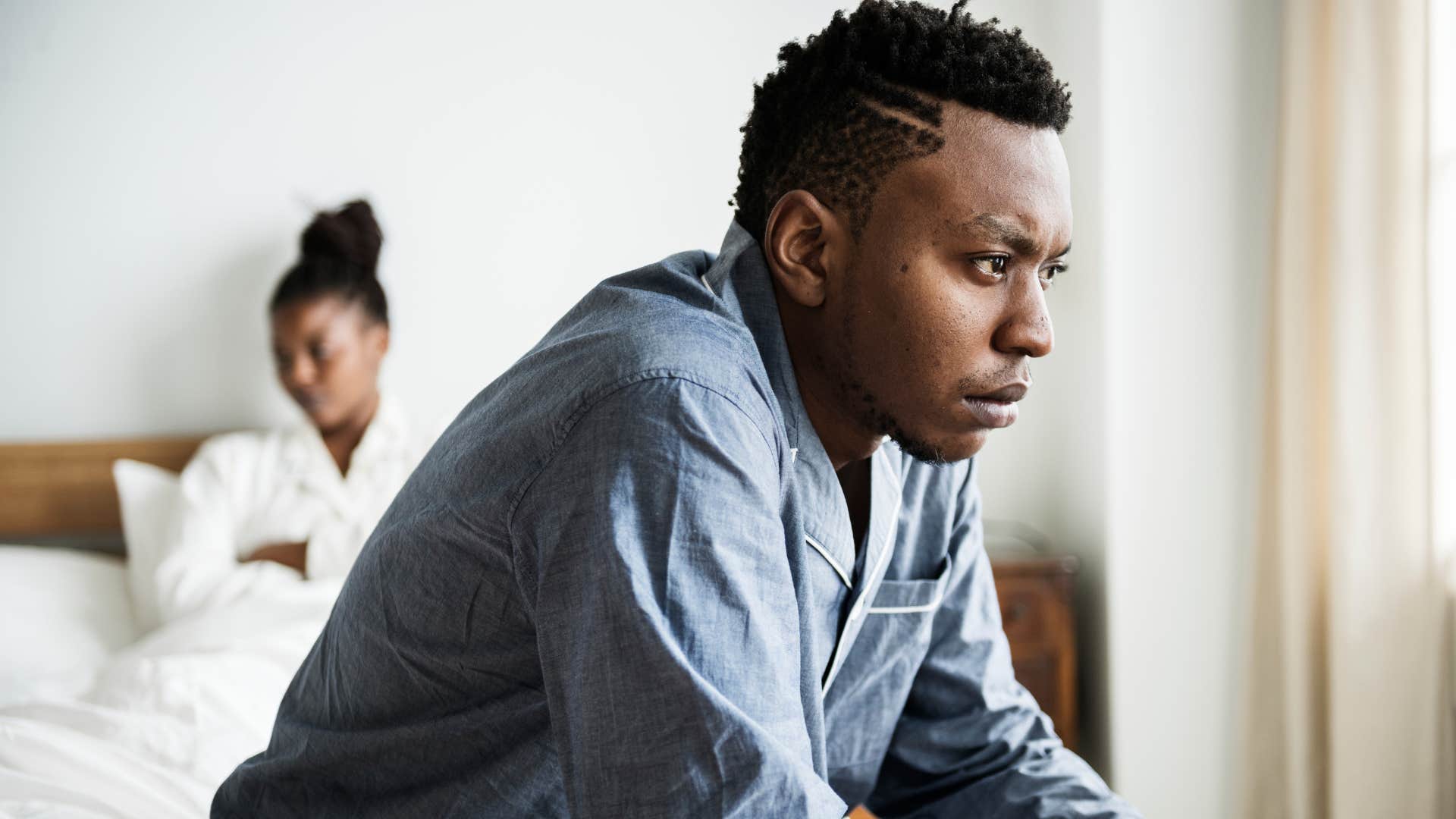 exhausted man sitting on bed