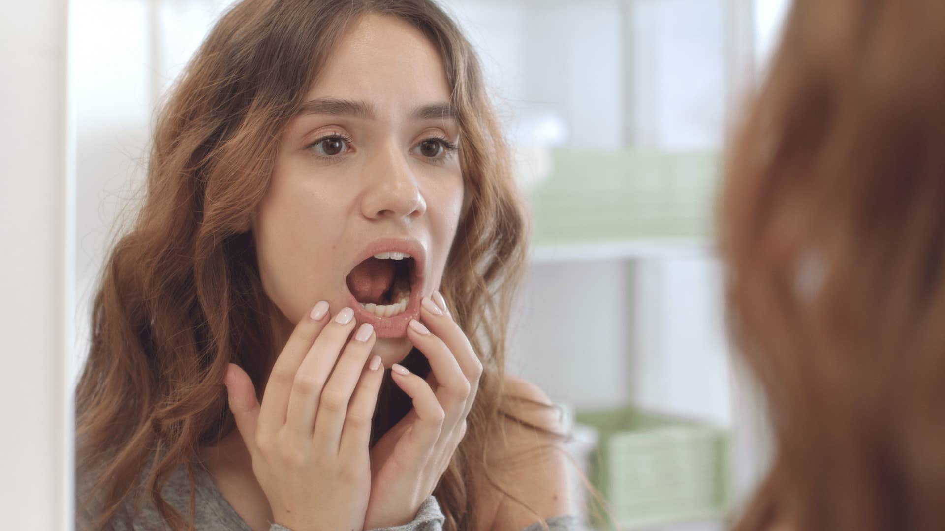 woman looking at her teeth in mirror