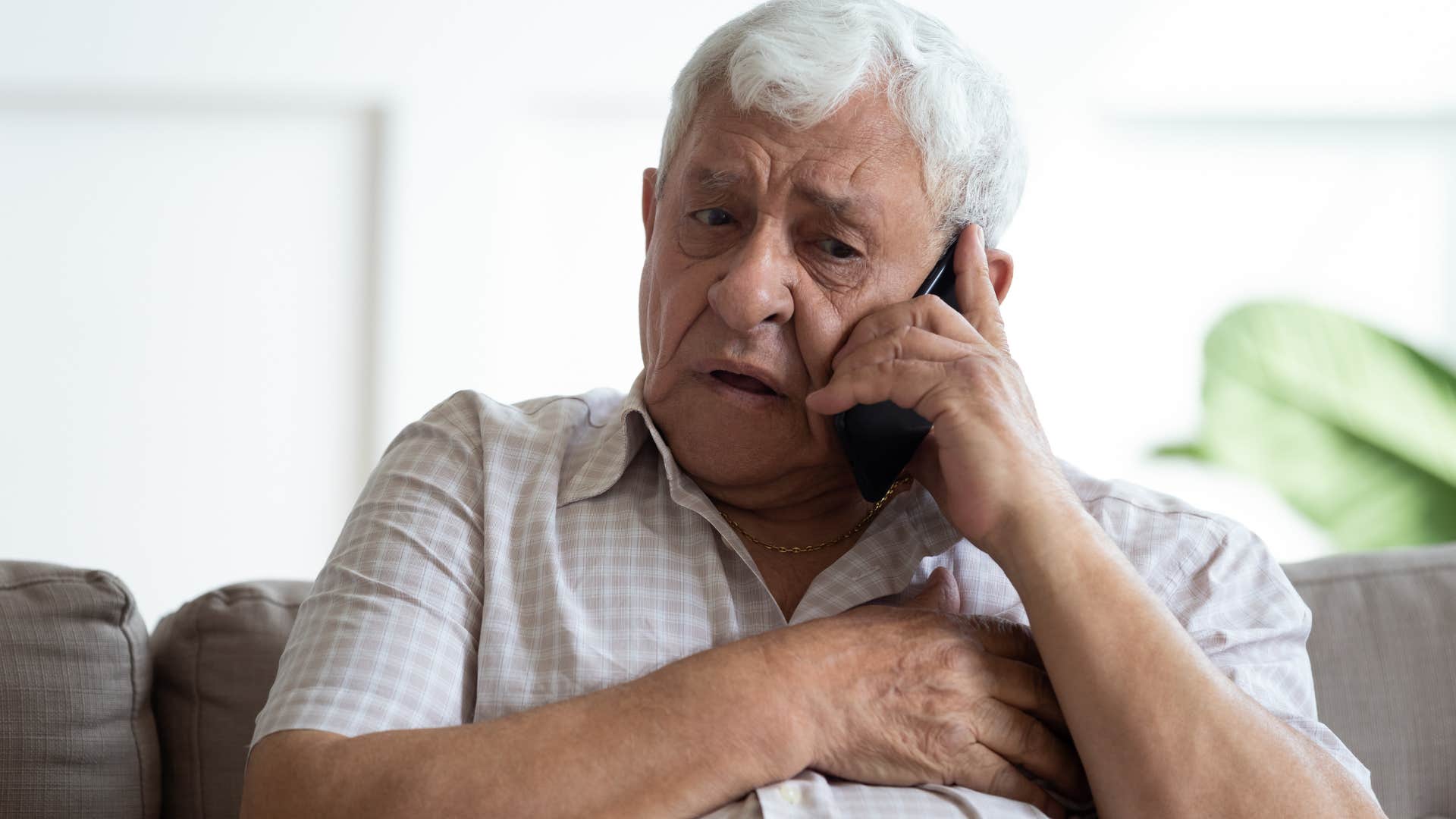 older man looking upset talking on the phone