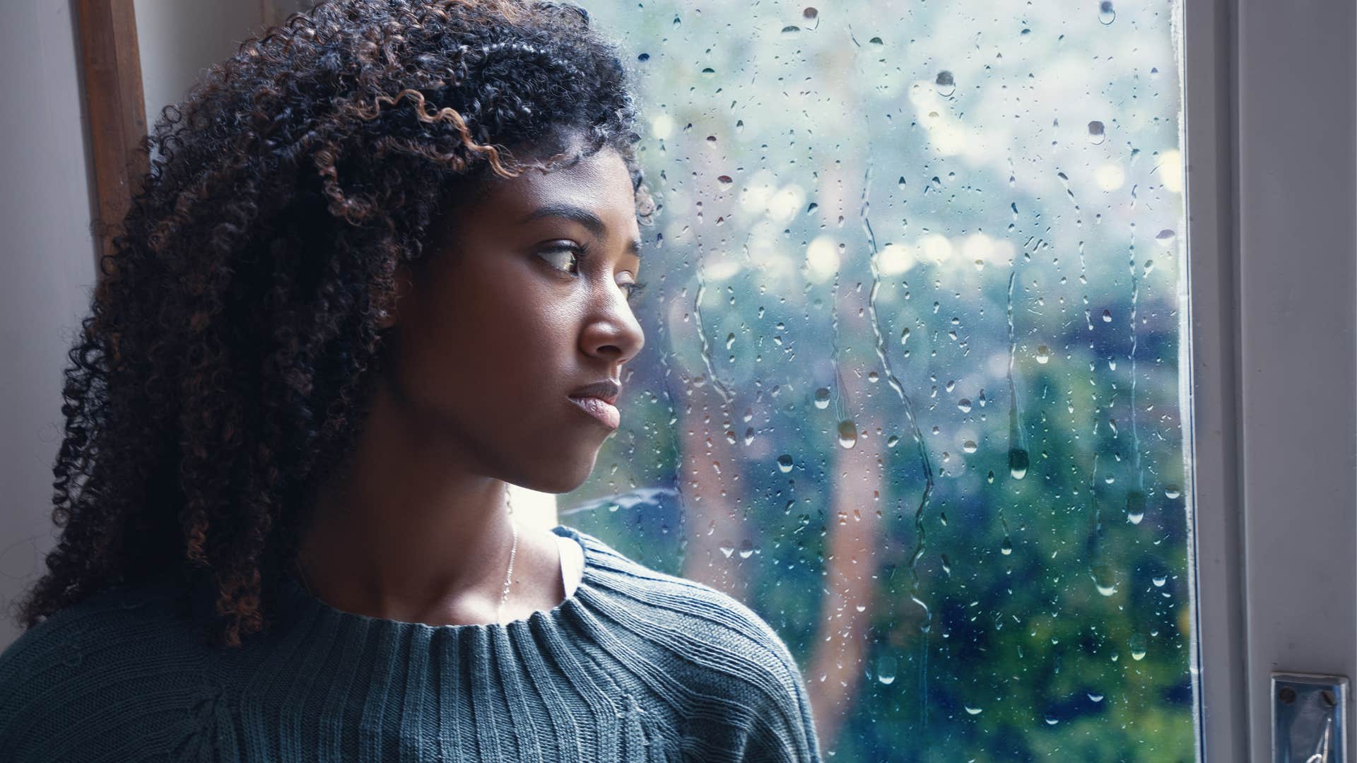 young adult woman staring out the window