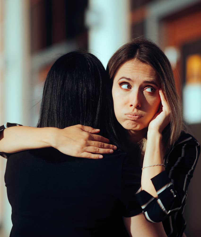 woman rolling her eyes while hugging her friend