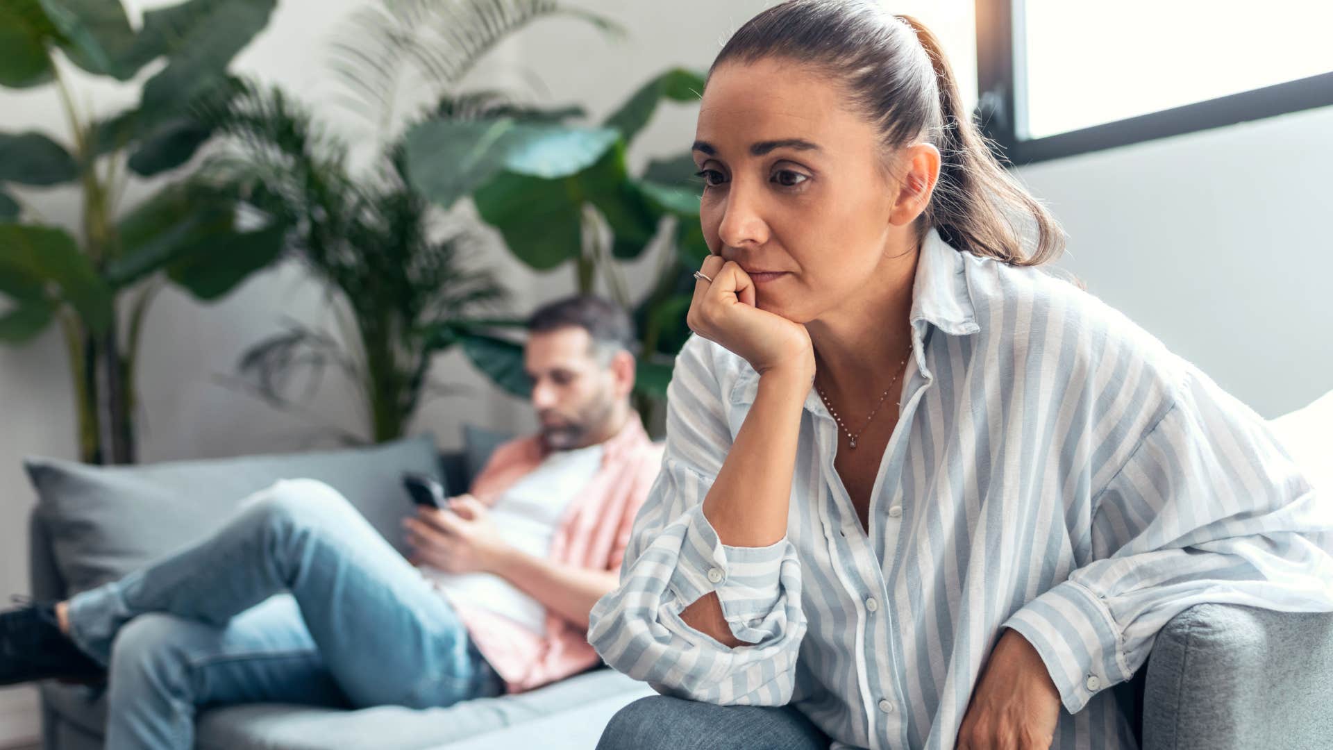 sad woman turned away from distracted husband