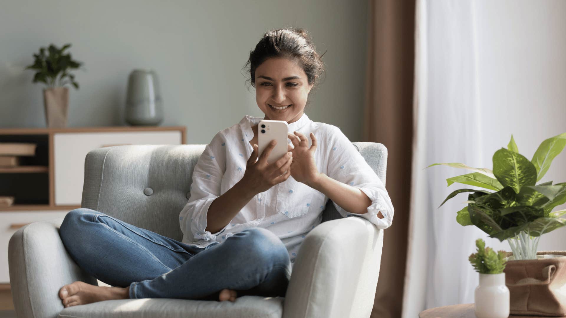 woman smiling while texting on phone