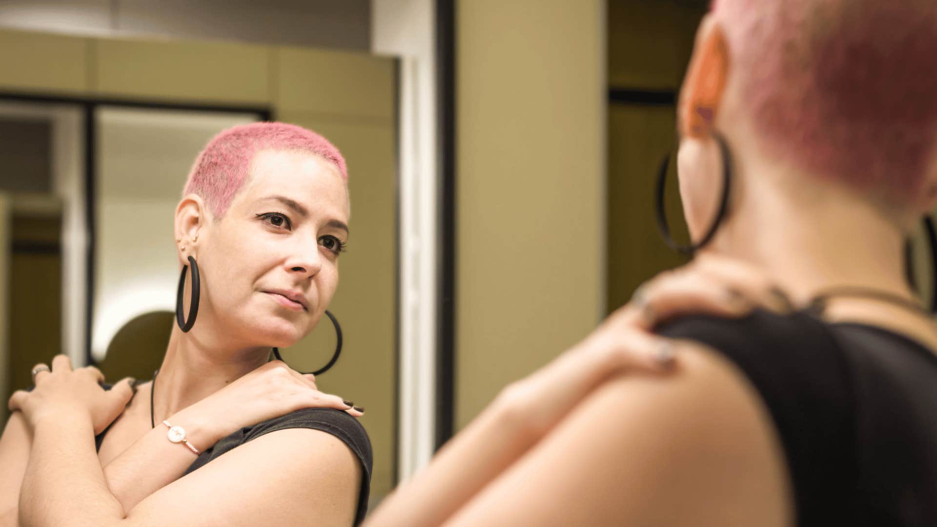 Woman looking in mirror and hugging herself