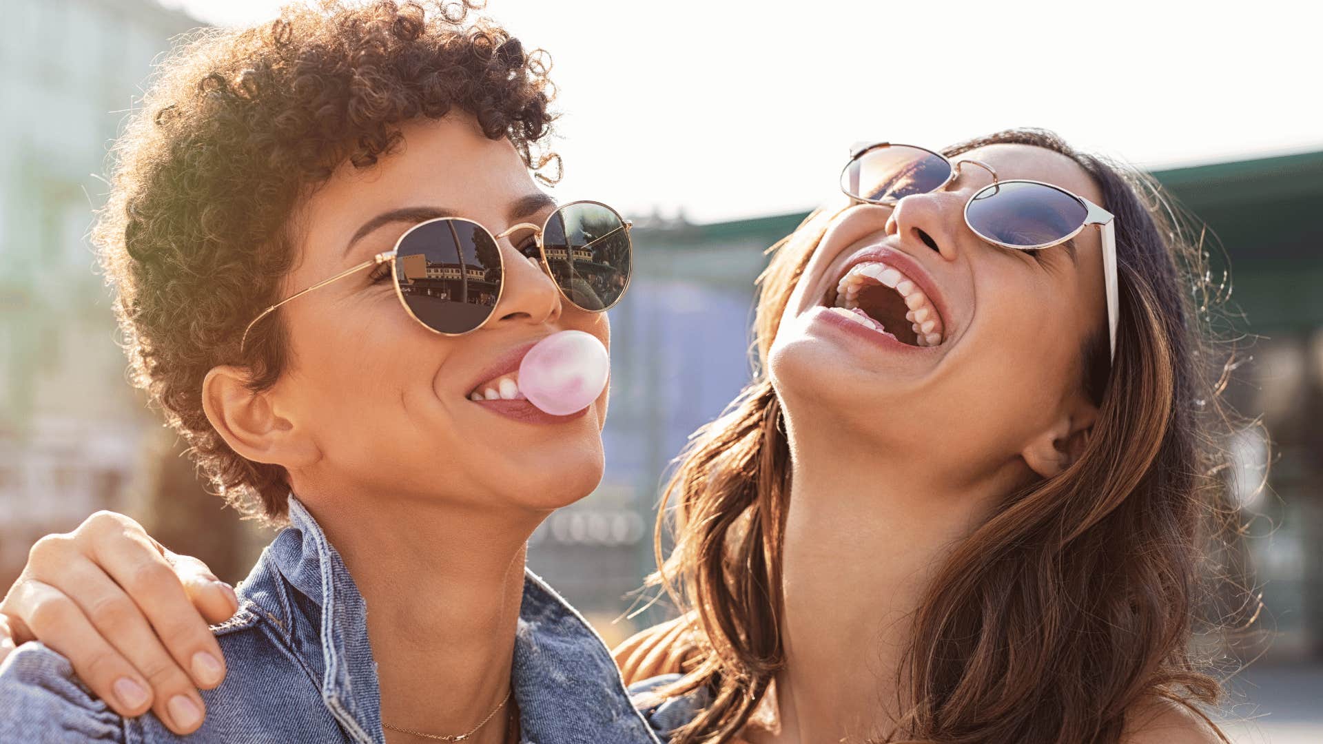 One person blows a bubble gum bubble and the other person laughs