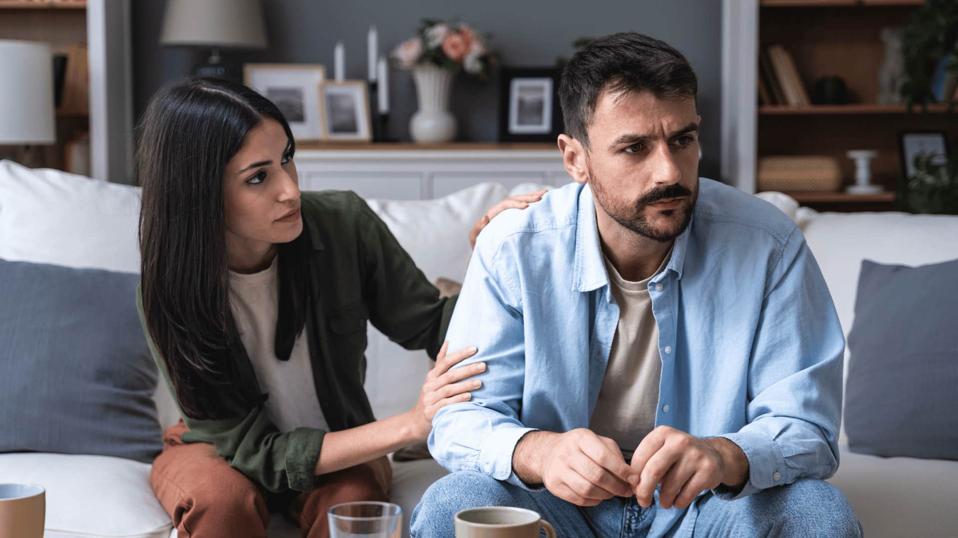 man ignoring woman trying to talk to him on couch