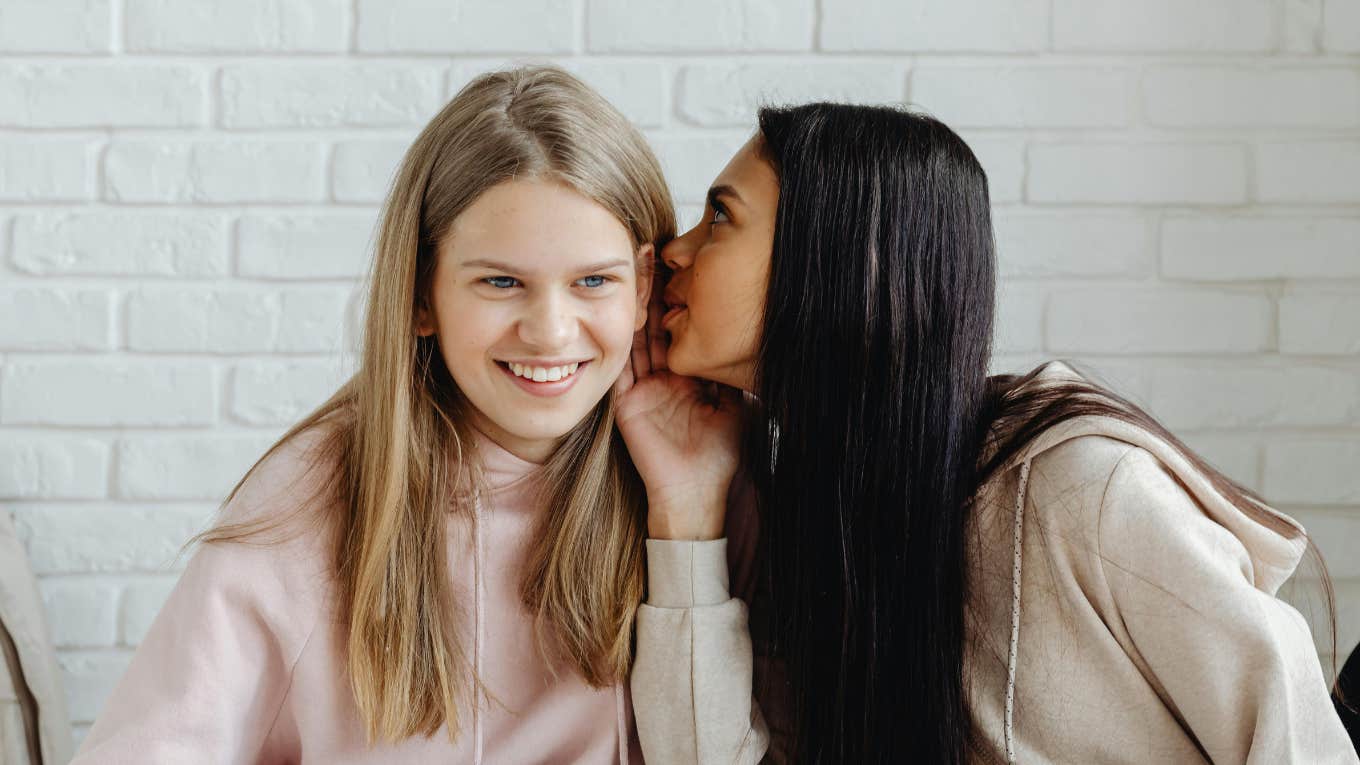 A girl whispering to another girl