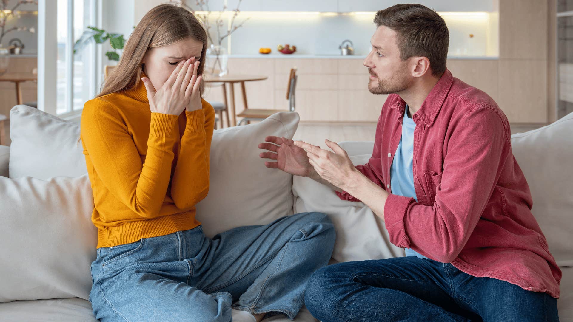 woman crying while man yells at her on couch