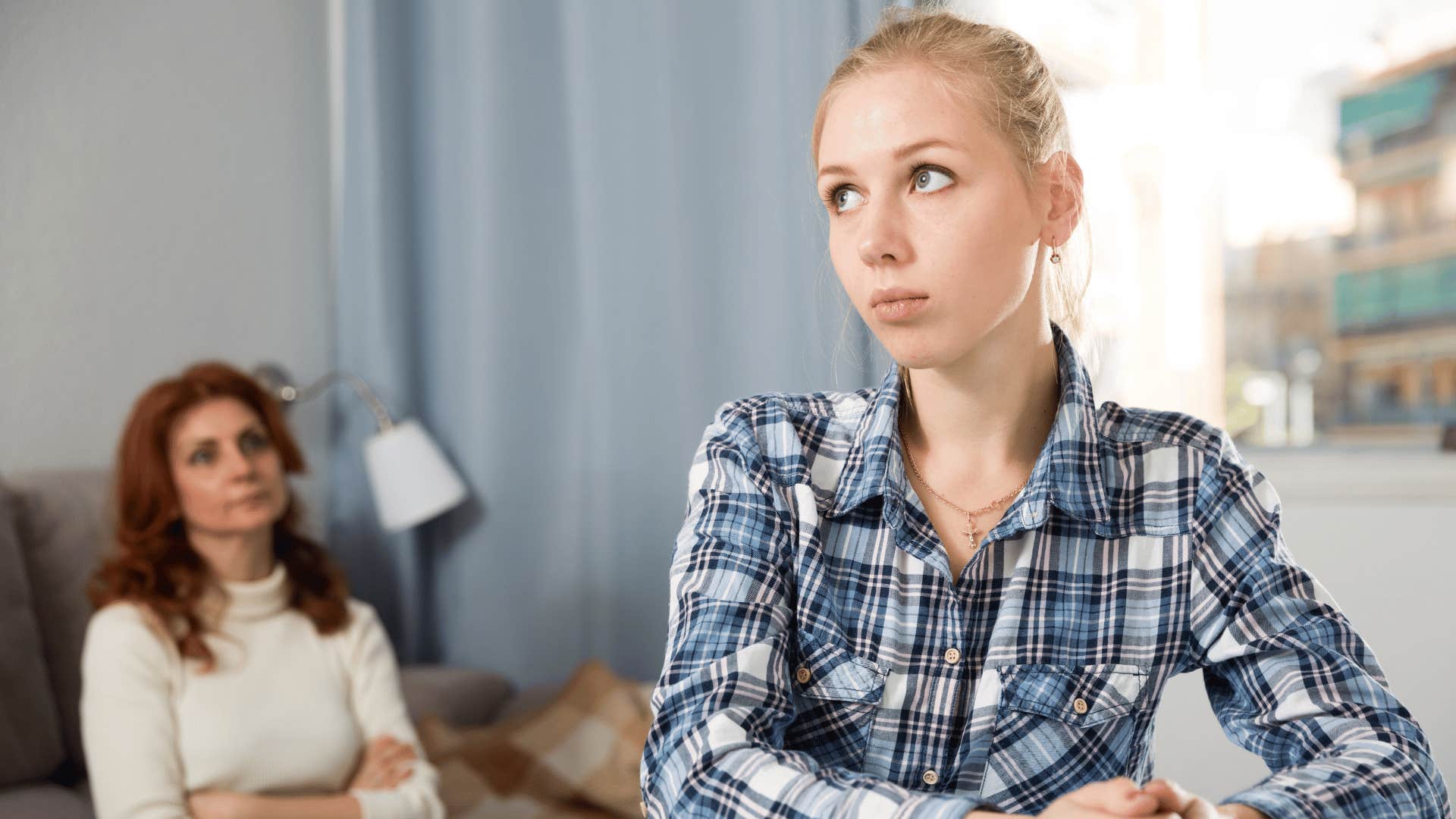 daughter looking annoyed as mom crosses her arms