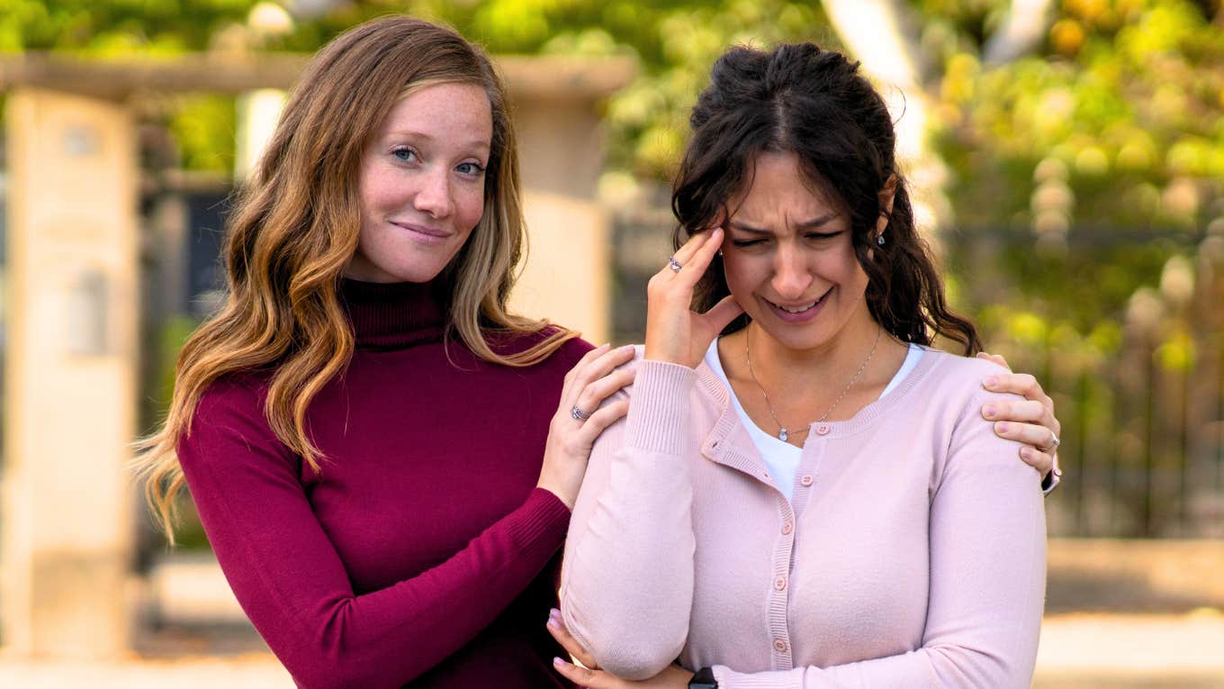 Happy false friend consoling a desperate woman in the street