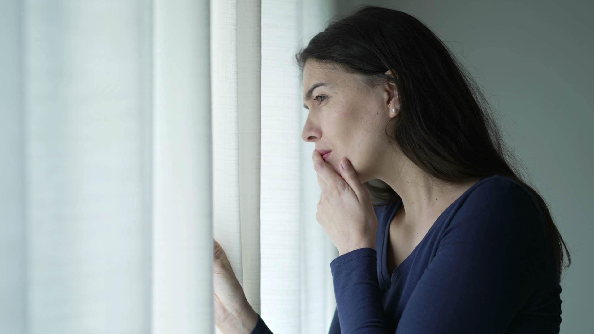 paranoid woman looking out the window