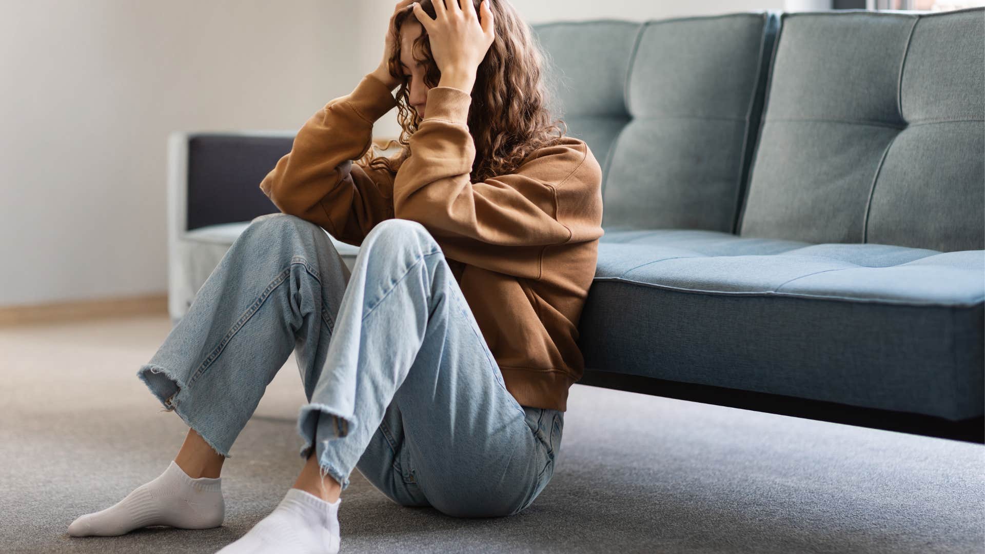 woman holding her head in her hands on the floor