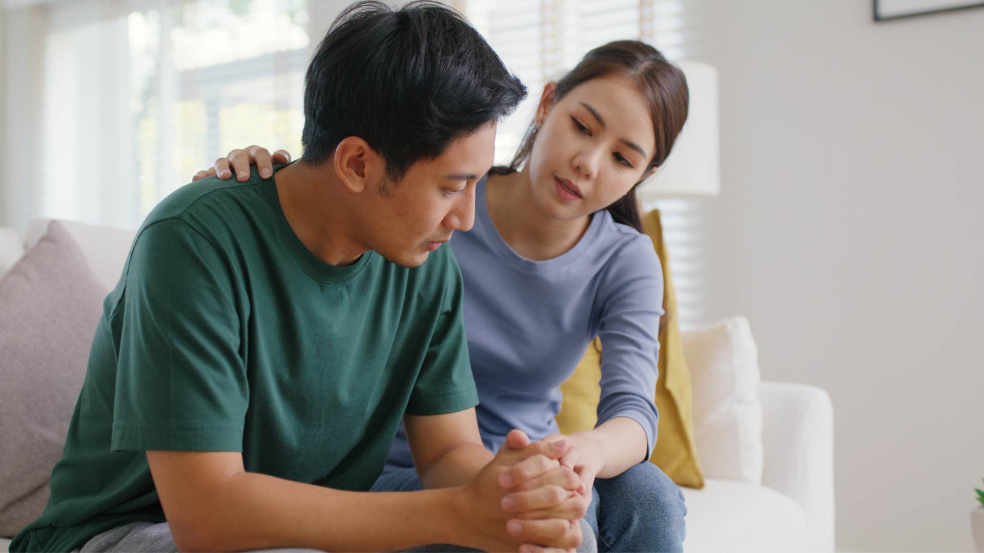 wife comforting husband on couch