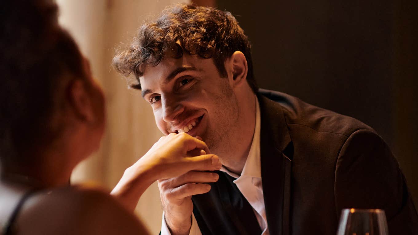 masculine gentleman in elegant attire kissing hand of girlfriend during date