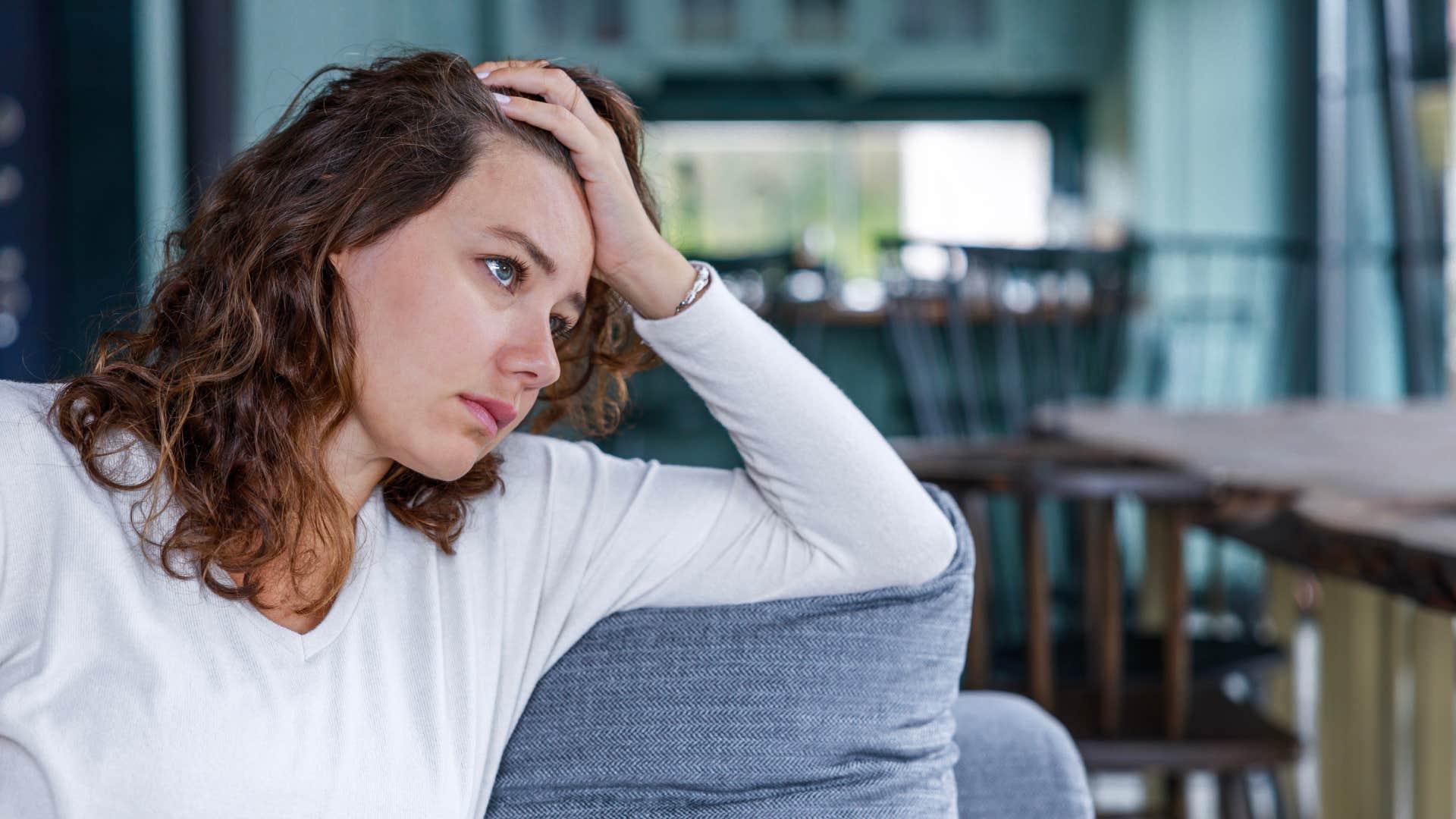 young woman sitting alone and thinking on couch