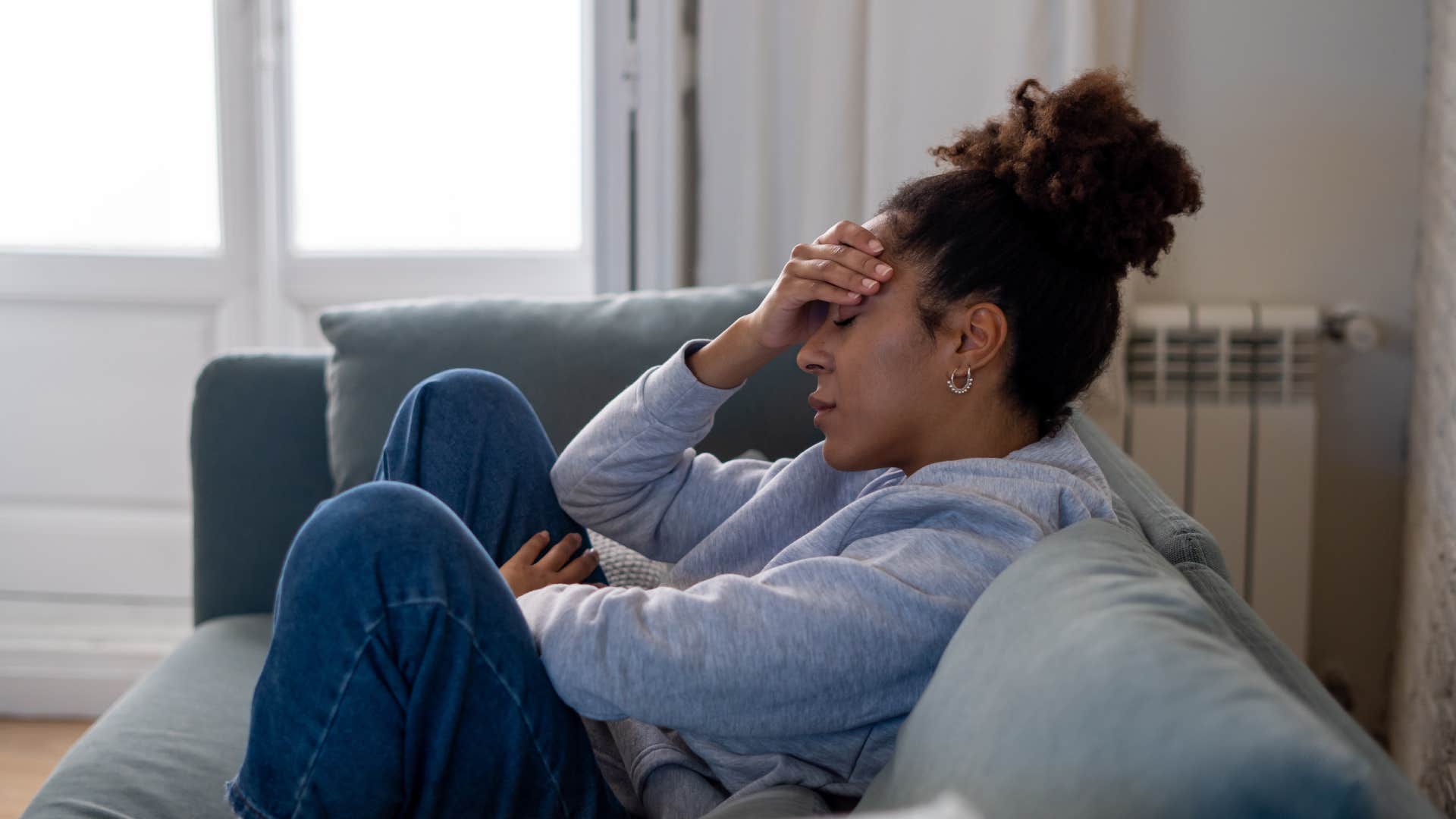 young woman sitting on couch with eyes closed