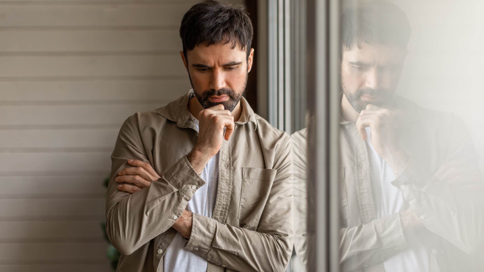 contemplative man leaning on a large window pane