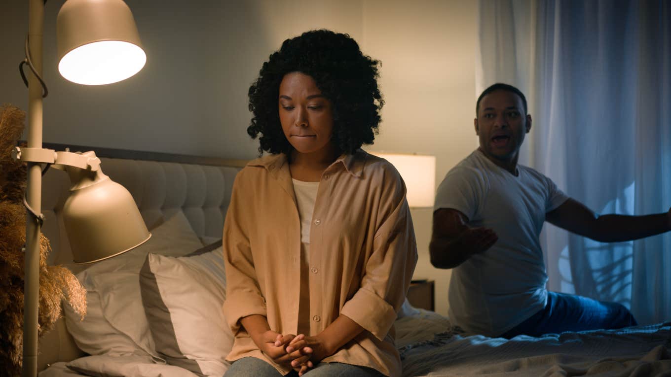 woman sitting on edge of bed during argument with husband