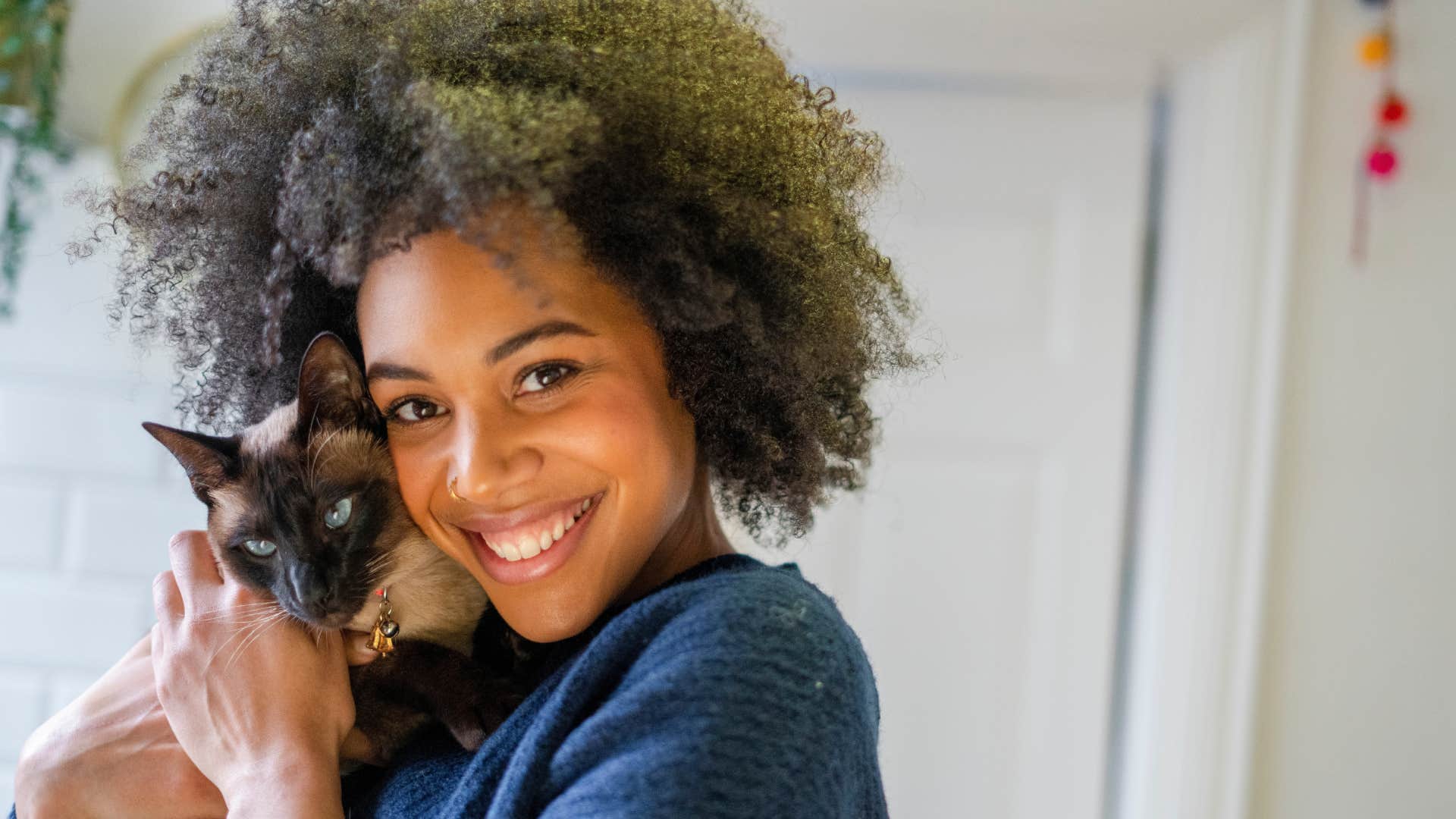 Portrait of smiling woman holding cat at home