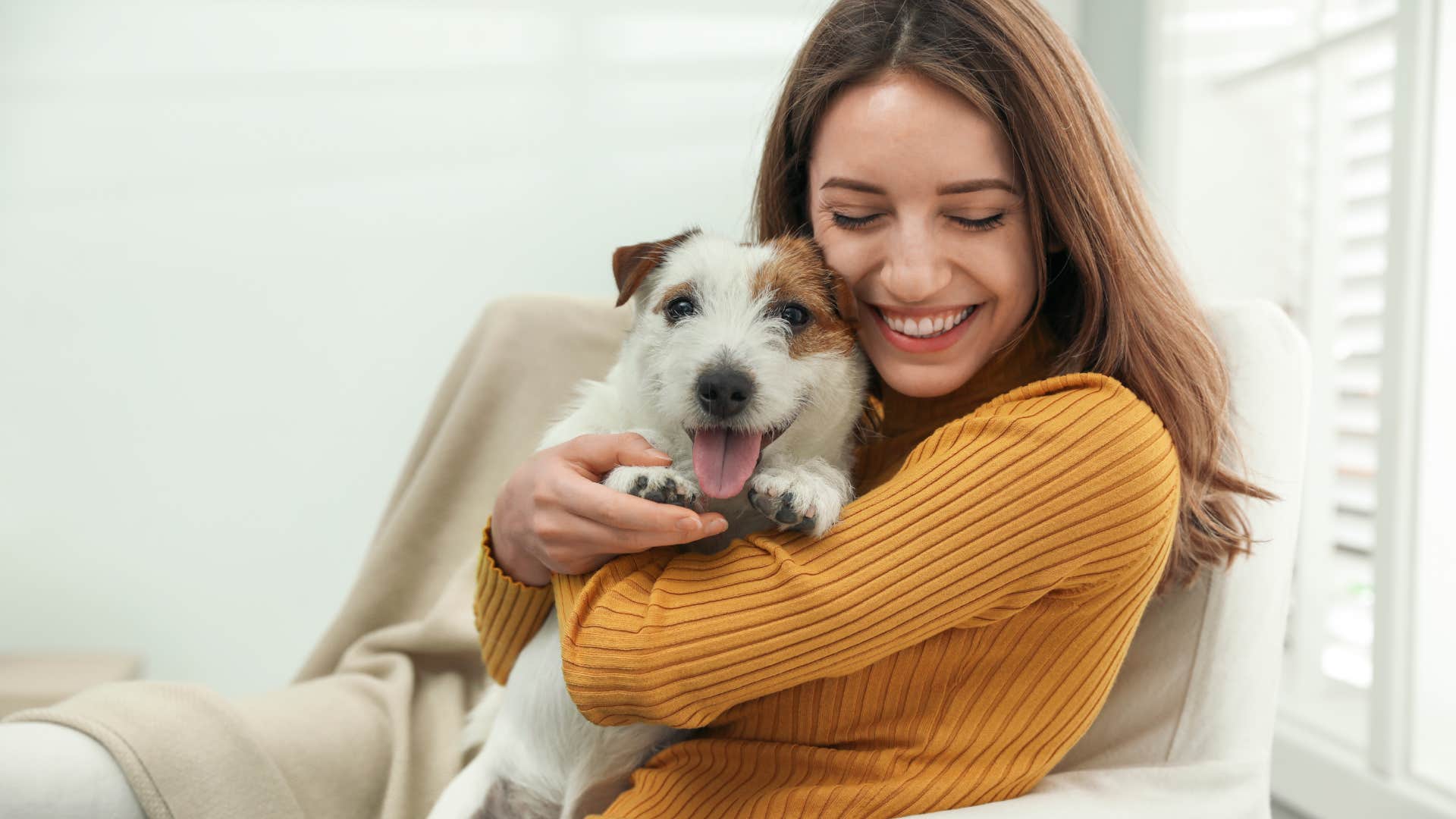 woman cuddling with dog on couch