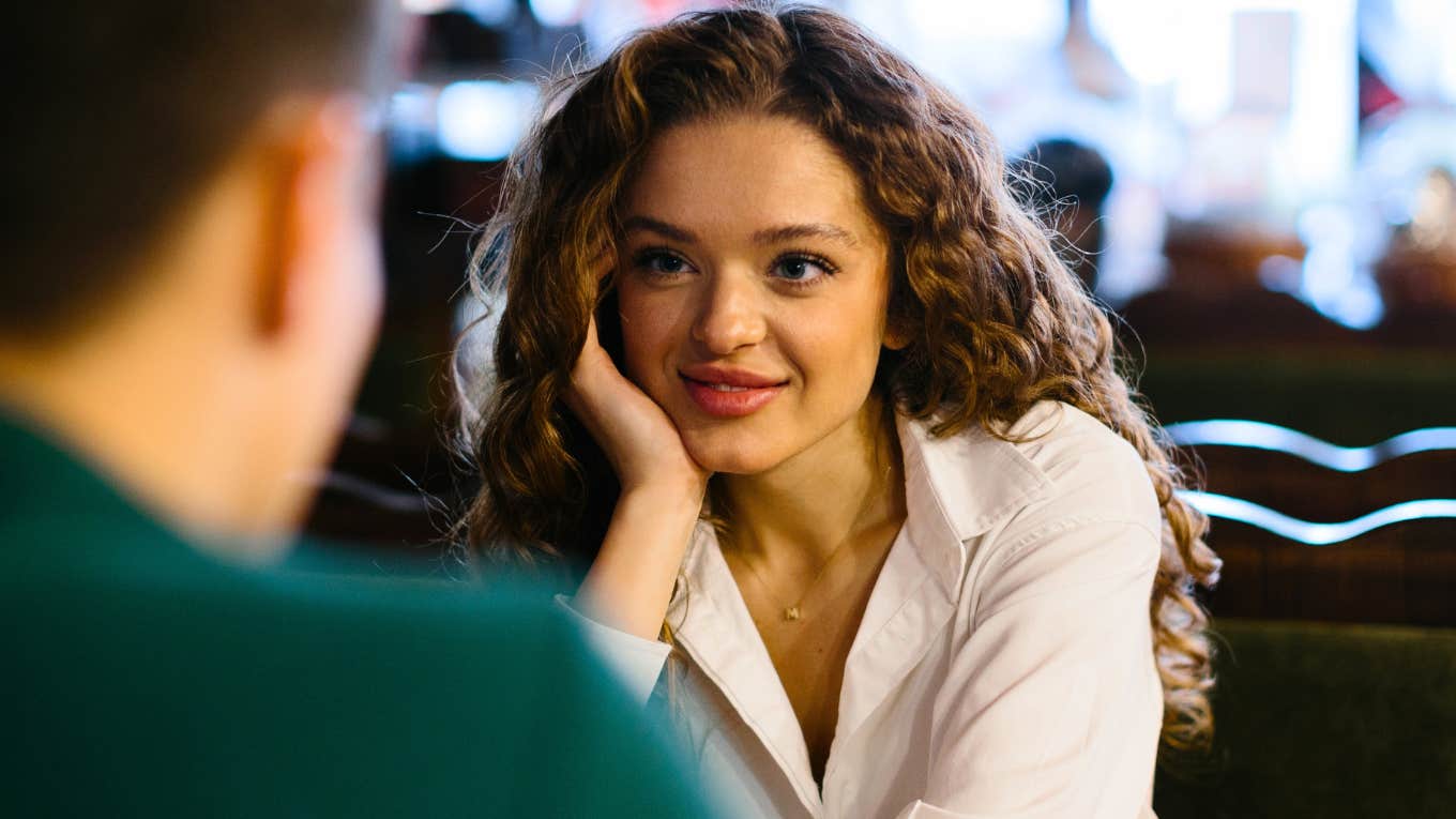 Smiling young woman talking to male friend at romantic date in cafe